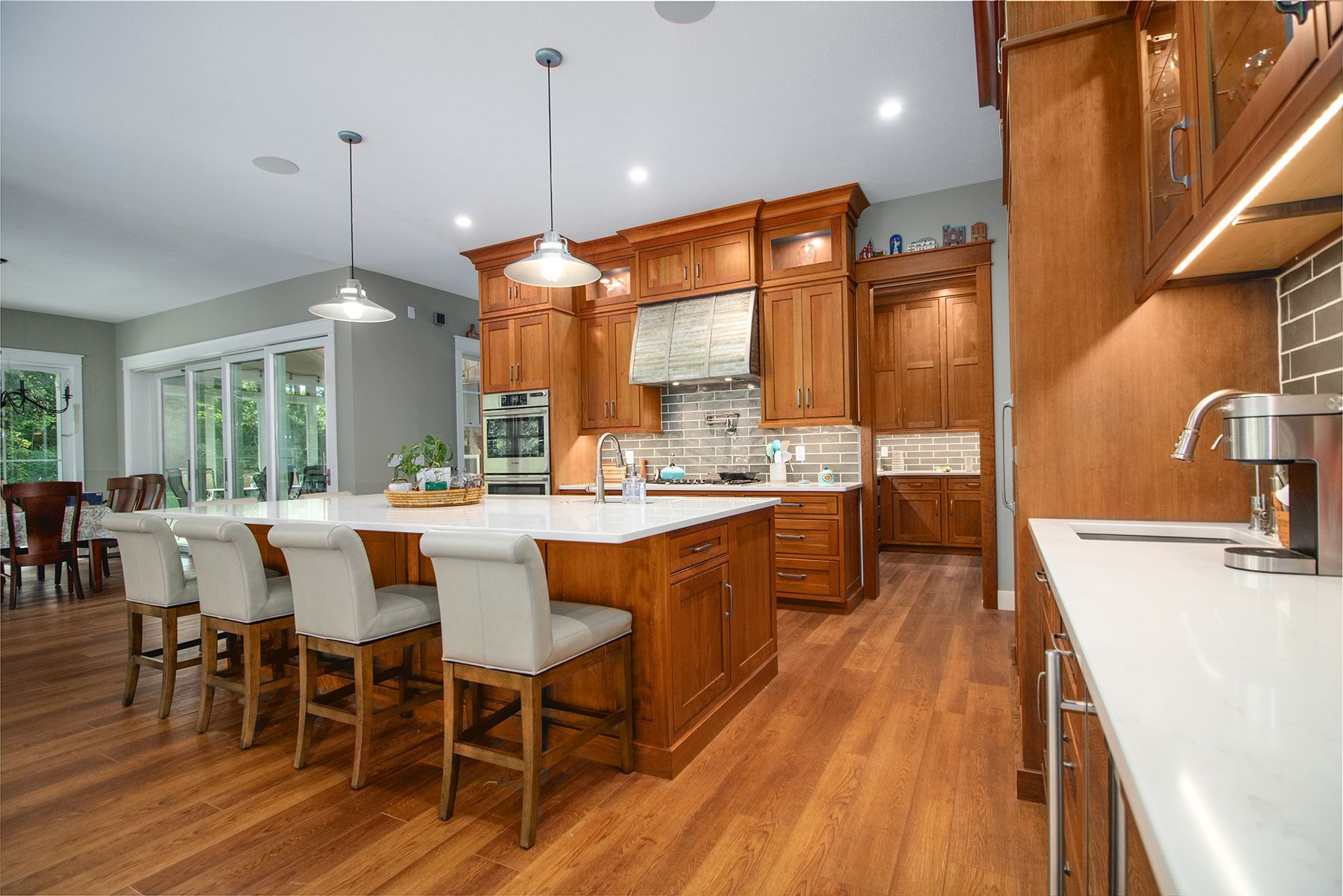 Modern kitchen with wooden cabinets, white island seating, and hardwood floors