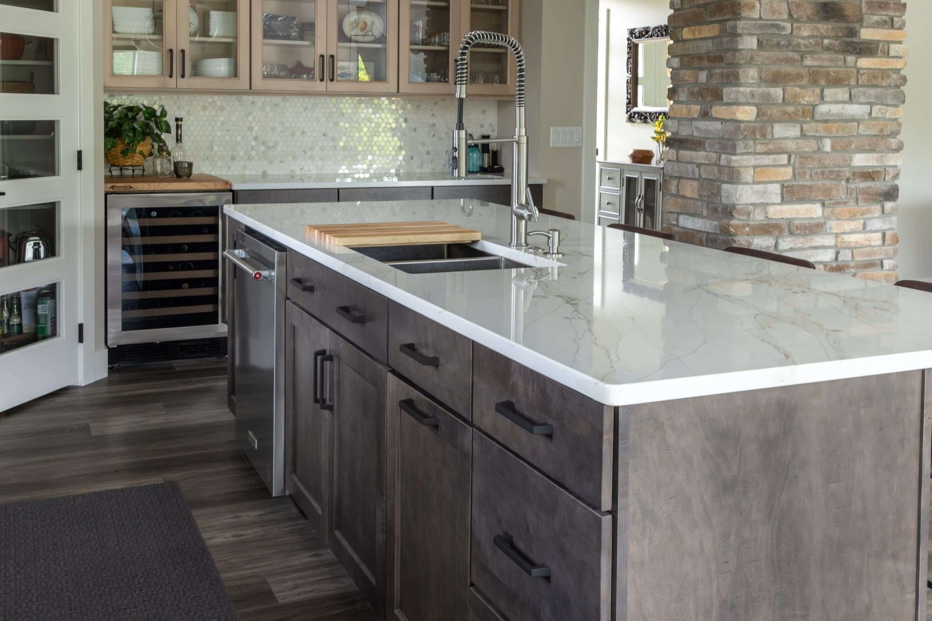 Modern kitchen with dark island cabinets, white countertop, and stone accent wall