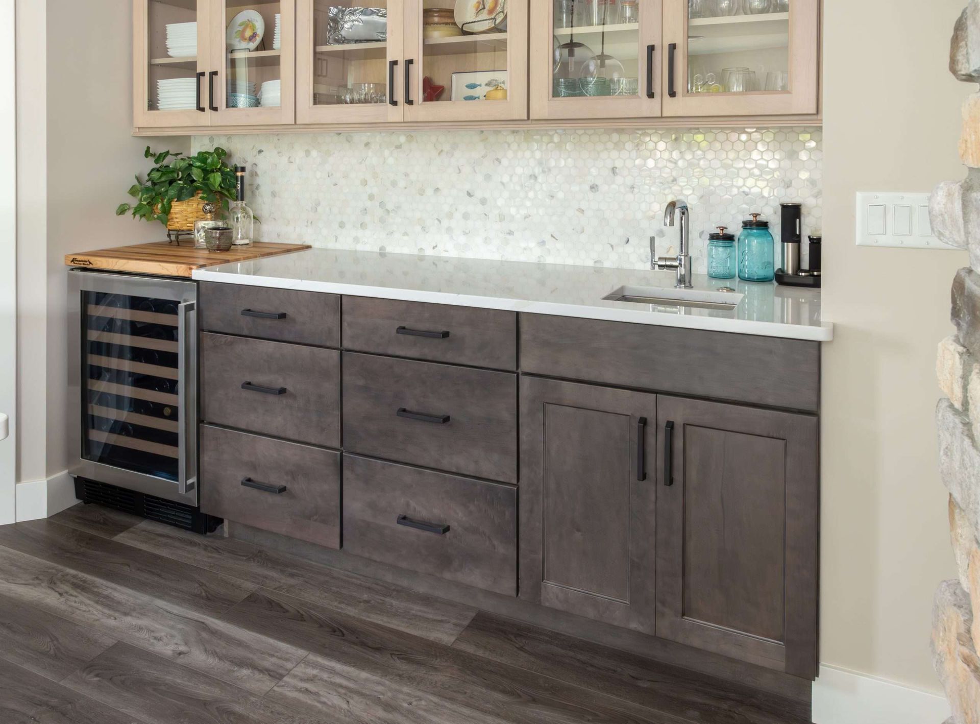 Modern kitchen wet bar with dark wood cabinets, white countertop, wine fridge, and sink