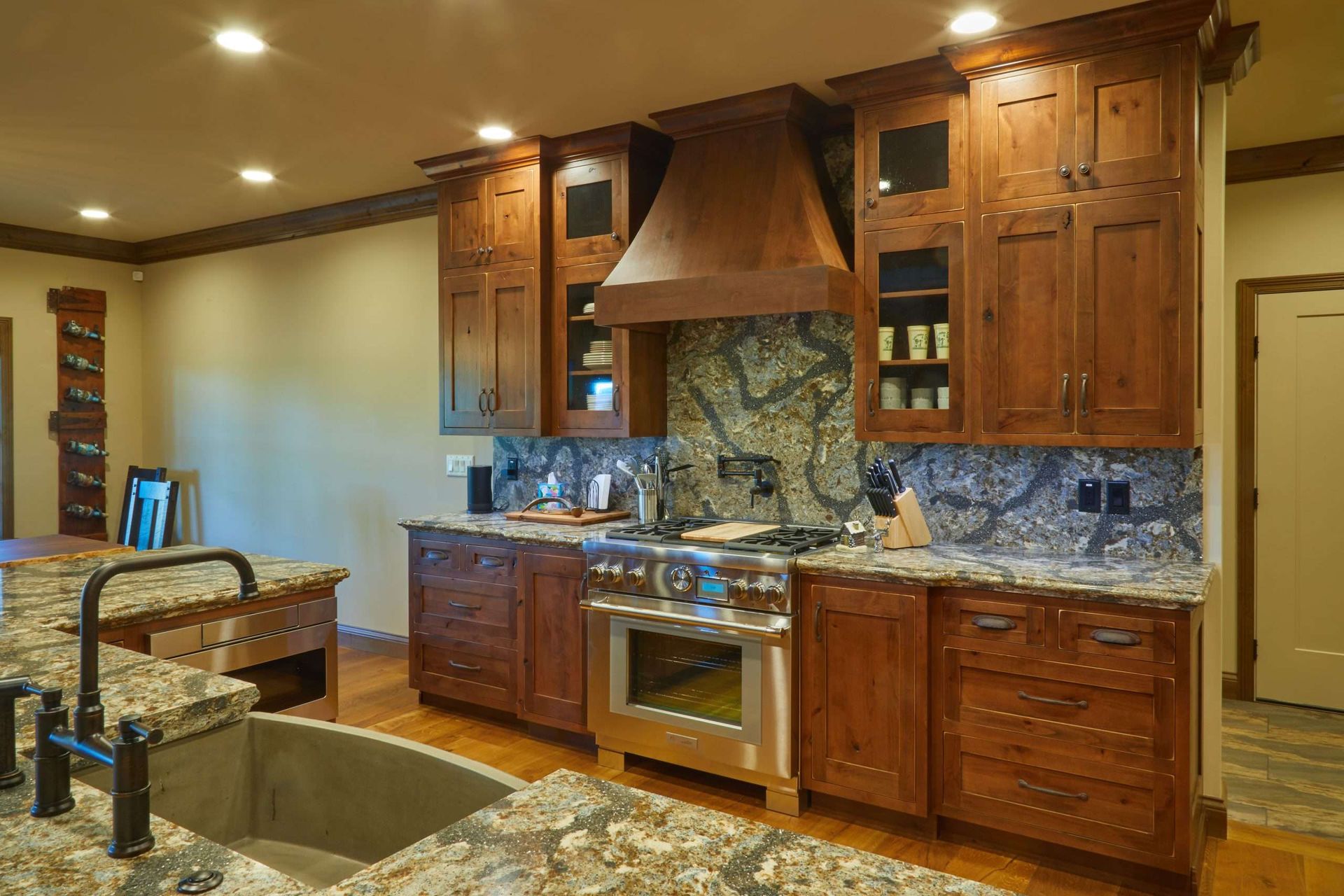 Warm kitchen with granite island, wood cabinets, stainless appliances, and stone backsplash
