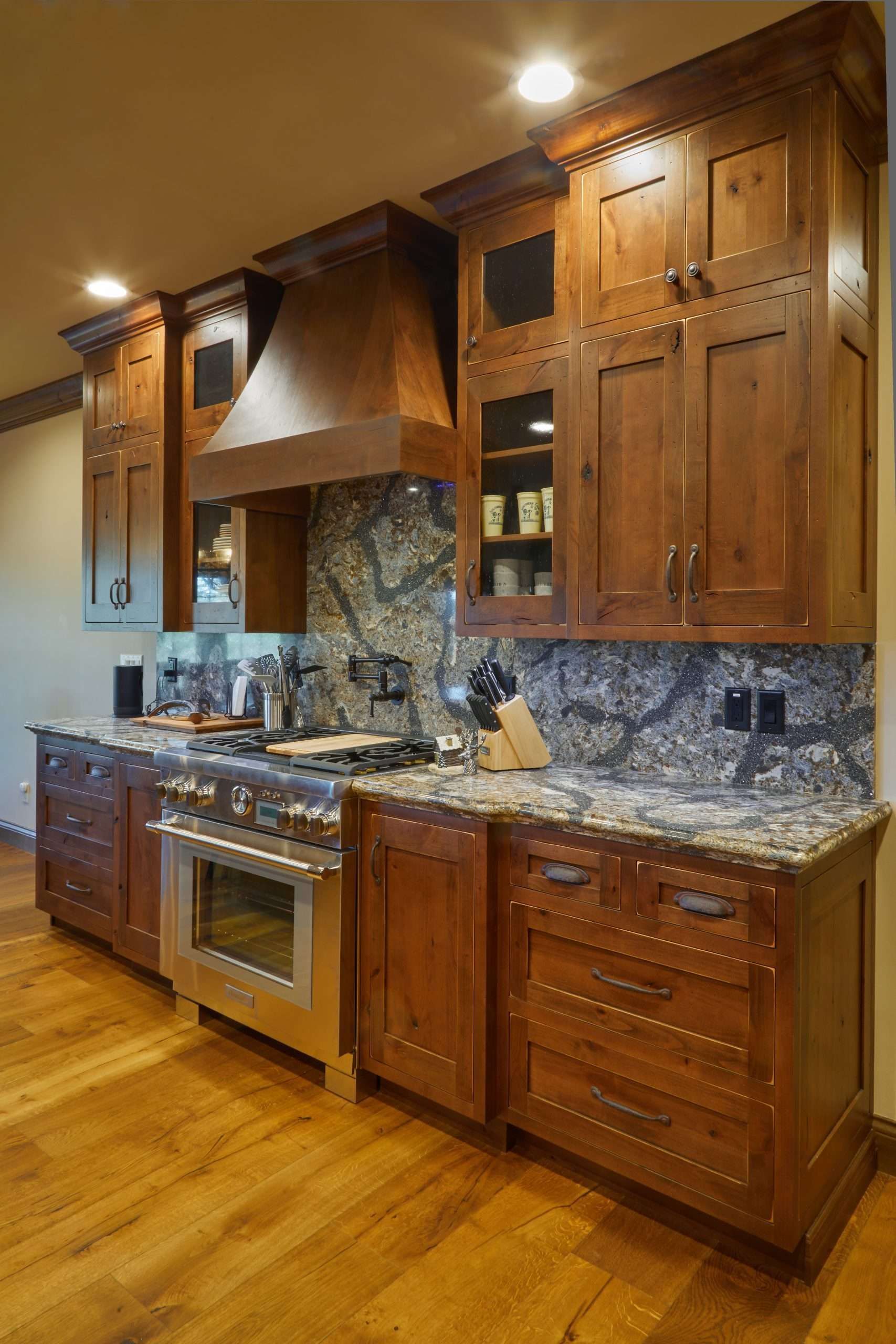 Wood-paneled kitchen with granite counters, stainless range, and warm recessed lighting