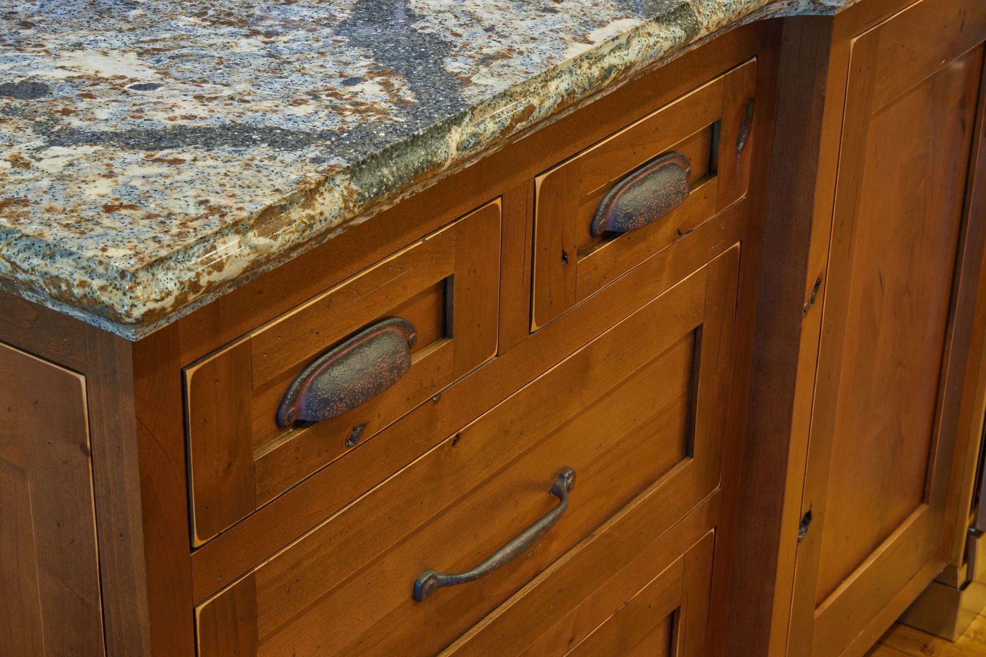Wooden kitchen cabinet with granite countertop and drawers, viewed close up