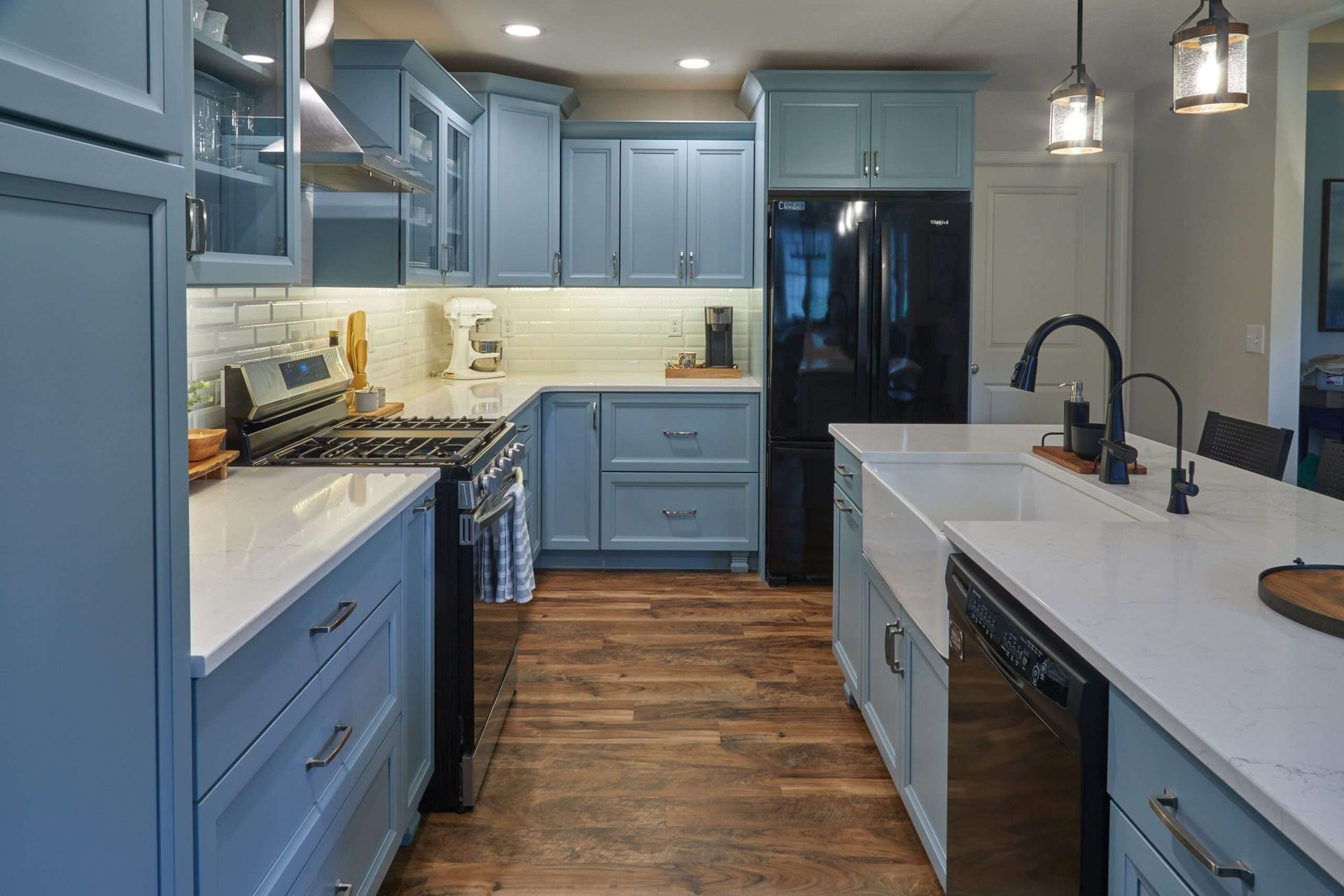 Modern kitchen with blue cabinets, white countertops, stainless appliances, and wood floors