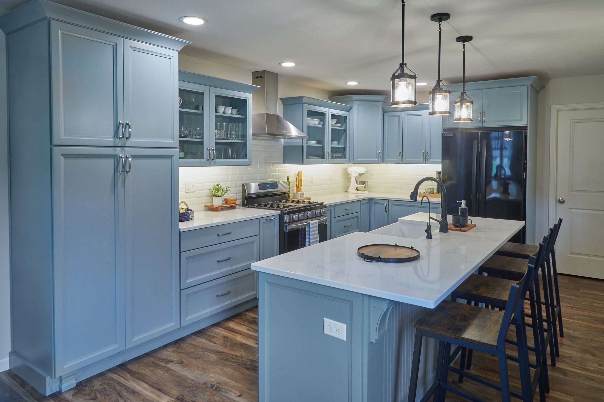 Modern gray kitchen with island, pendant lights, built-in cabinets, and black bar stools