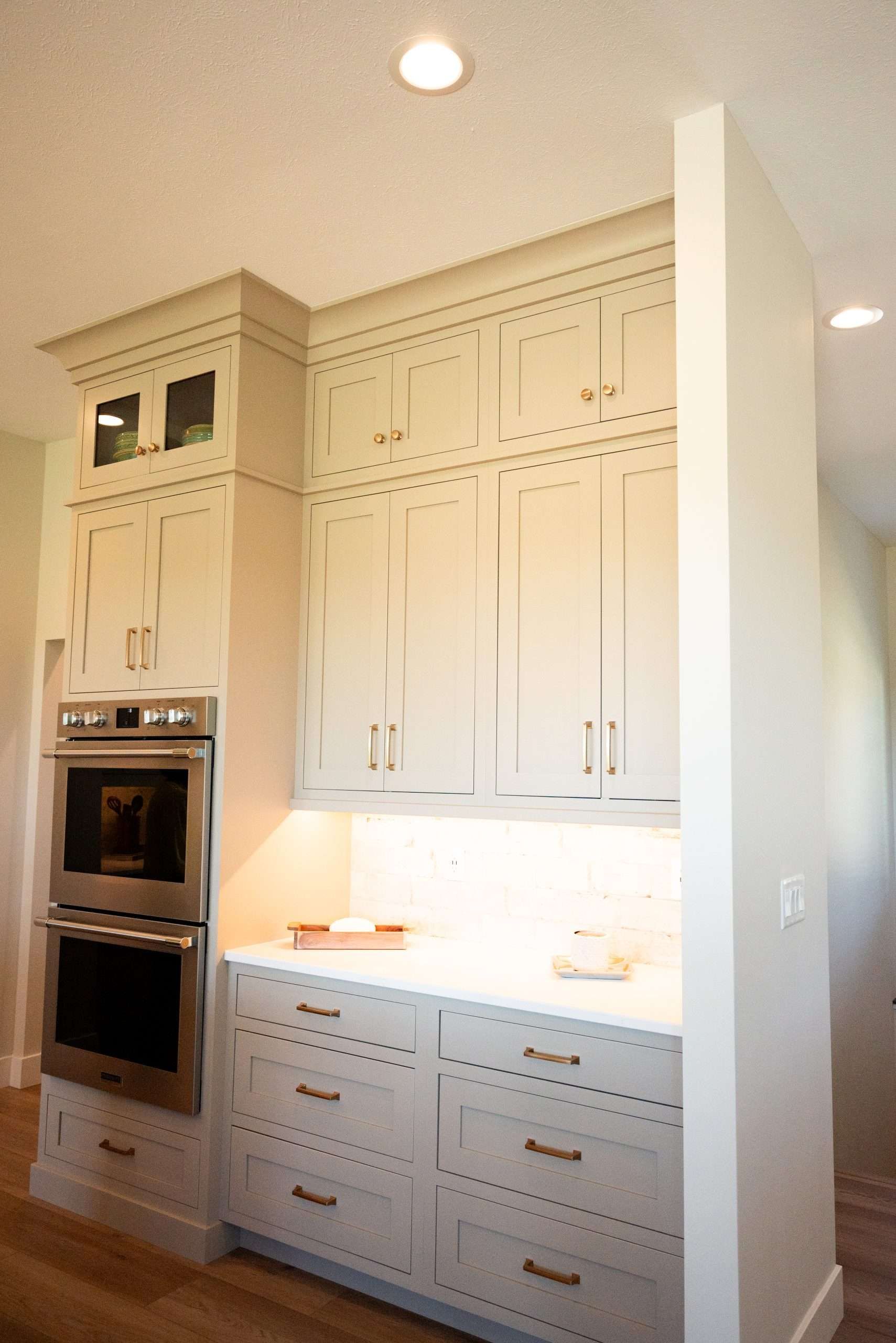 Built-in white kitchen cabinetry with double ovens and drawers under a bright countertop