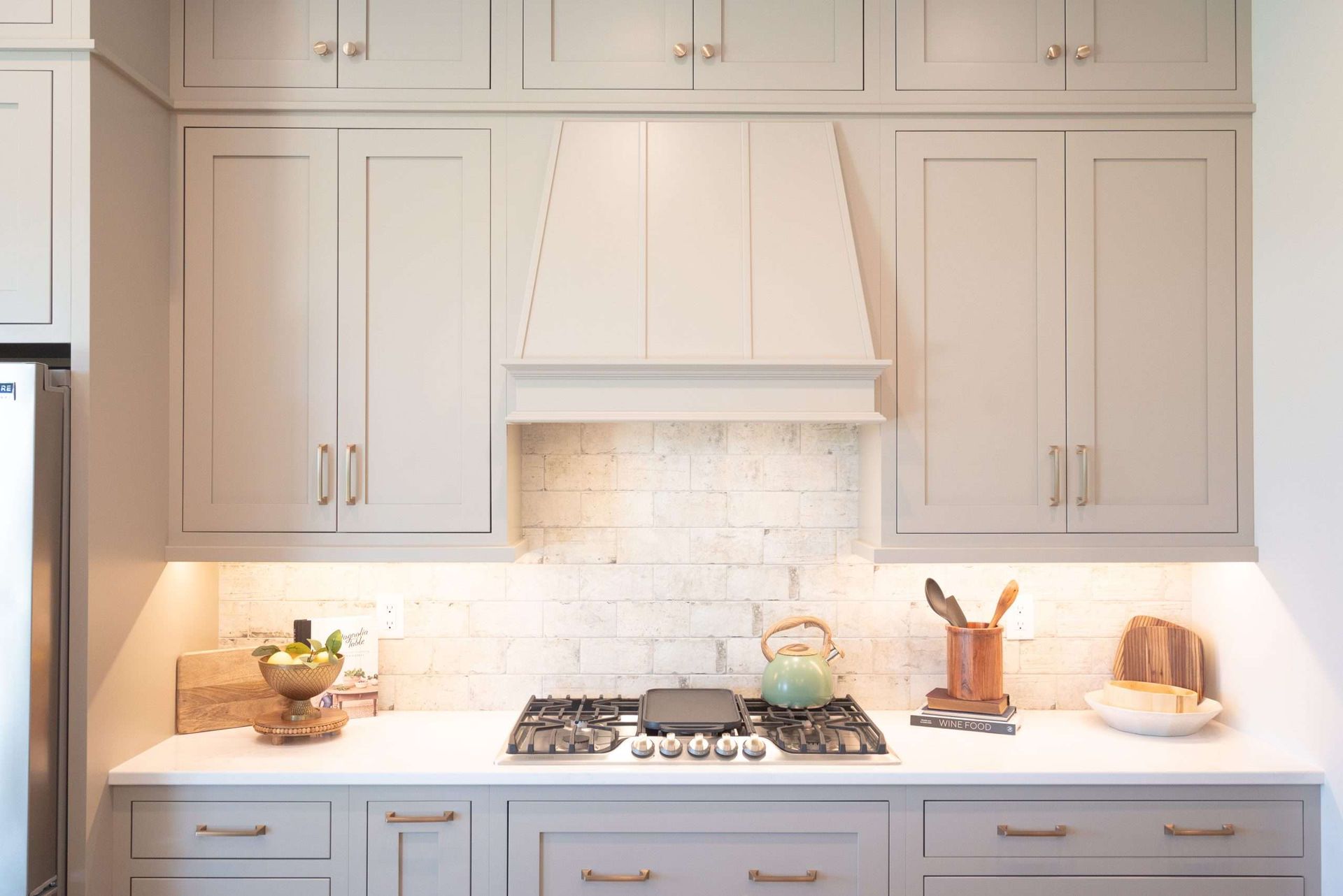 Bright white kitchen with cabinets, marble backsplash, gas range, and warm under-cabinet lighting