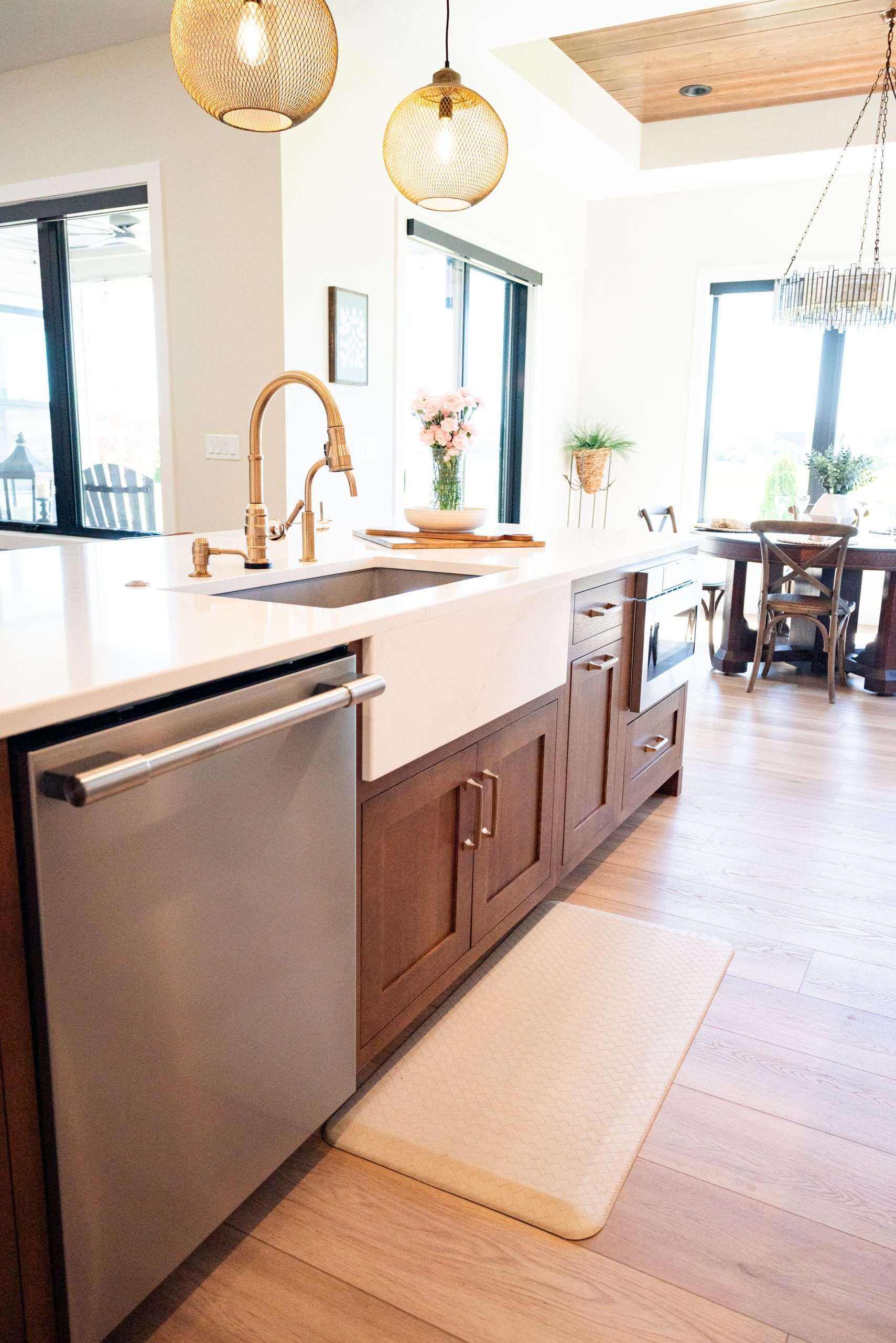 Bright kitchen with a farmhouse sink, wood cabinets, stainless dishwasher, and pendant lights