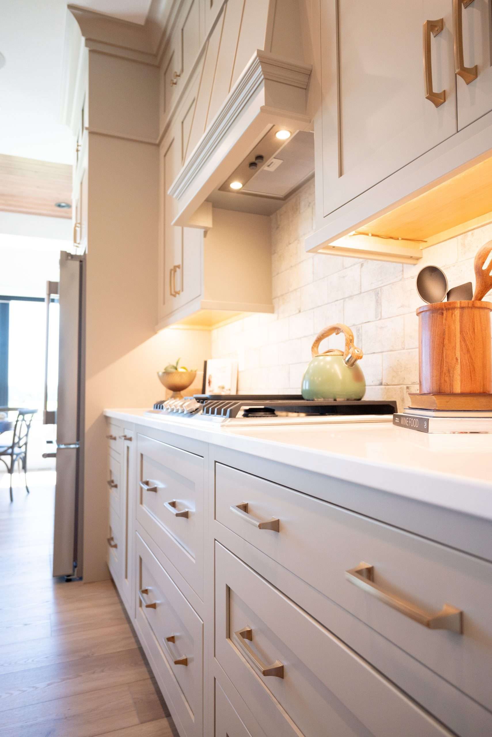 Bright white kitchen with built-in cabinets, countertop, stove, and warm under-cabinet lighting.