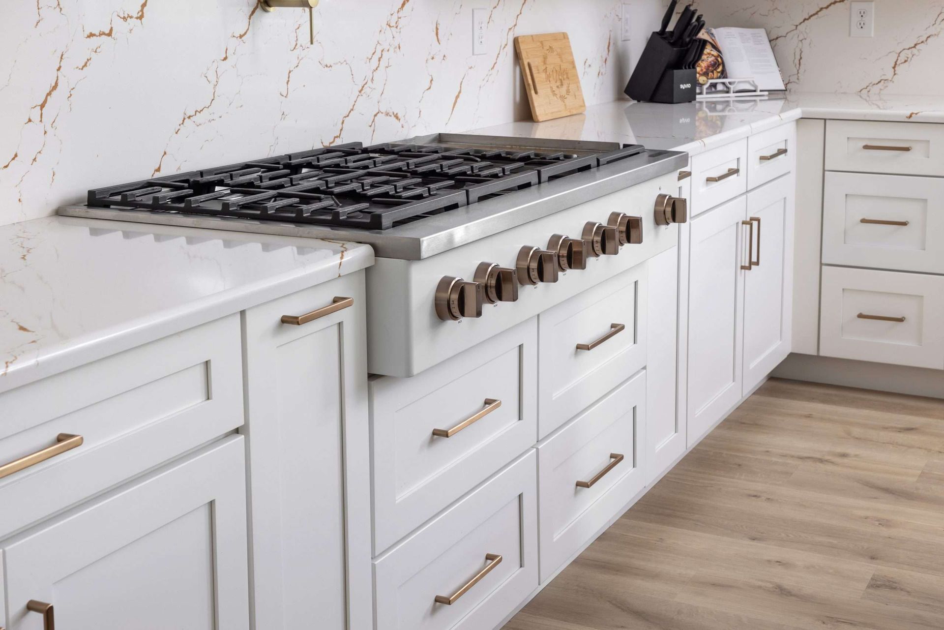 White kitchen with a large stainless steel gas range and drawers, viewed from the side