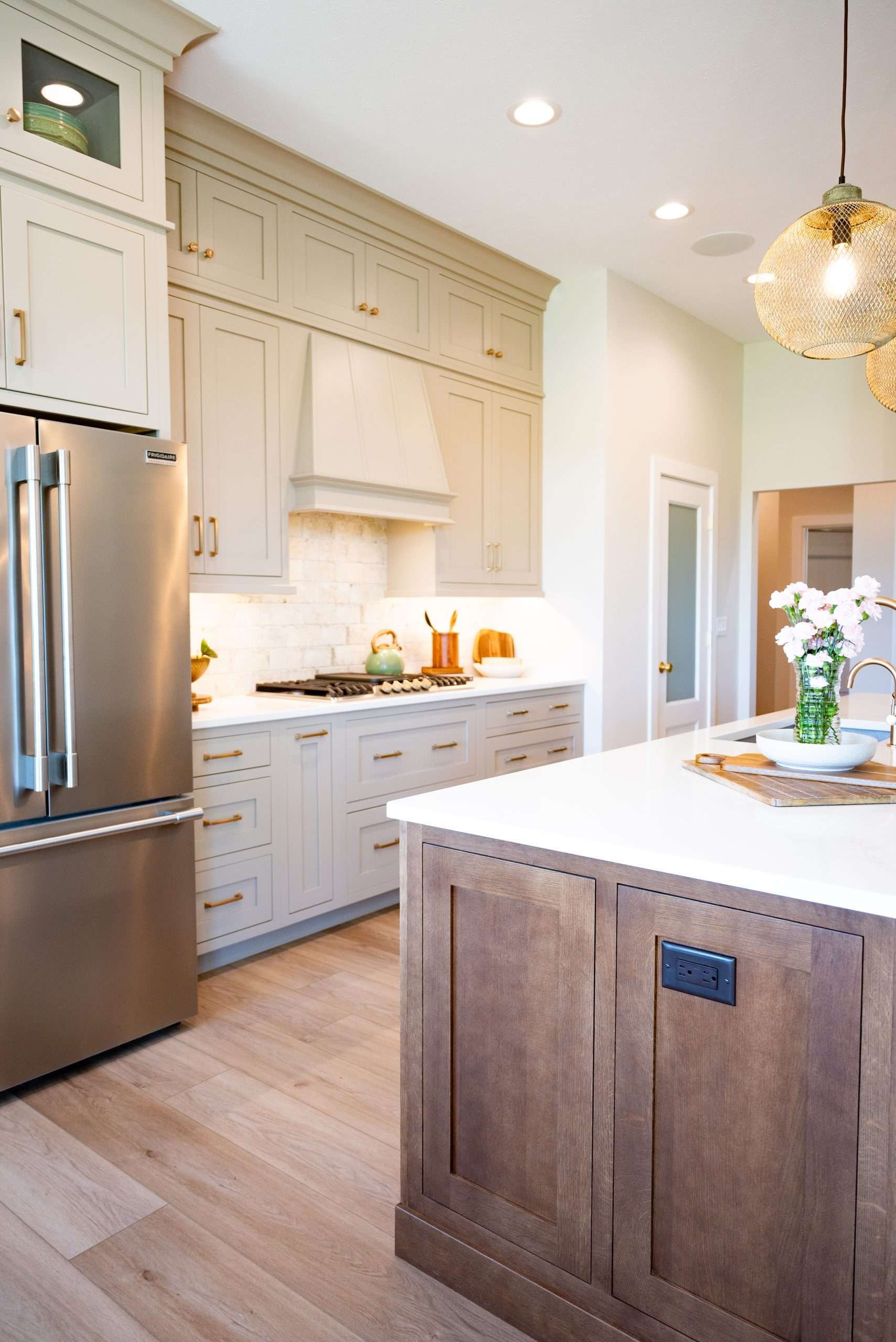 Bright, modern kitchen with white cabinets, stainless fridge, wood island, and pendant light