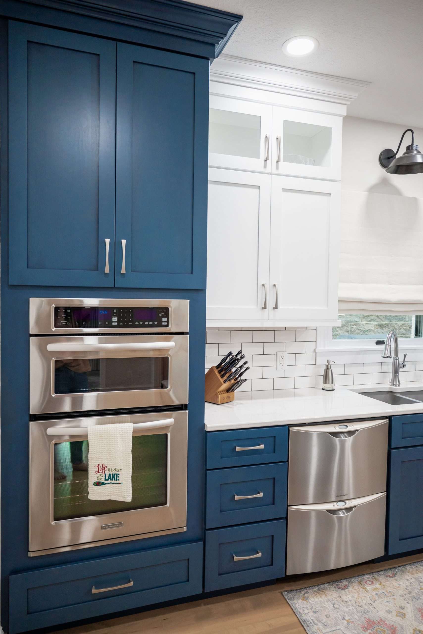 Modern kitchen with blue and white cabinets, stainless steel appliances, and a white tile backsplash