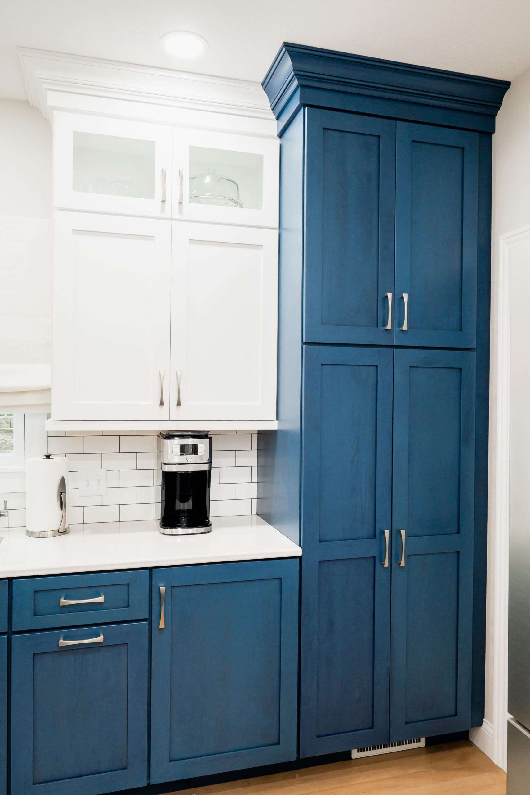 Blue and white kitchen cabinets with a coffee maker on the counter
