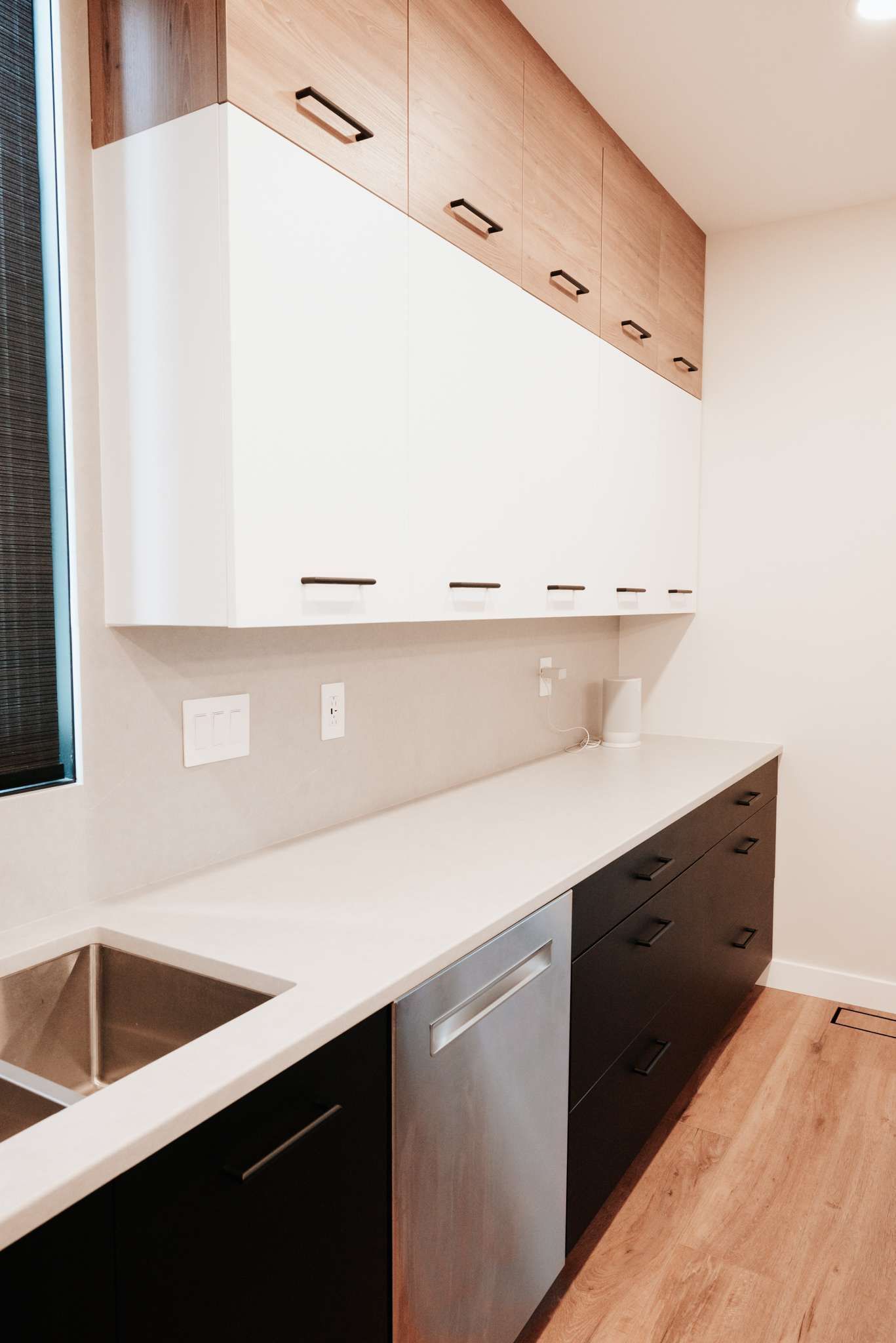 Modern kitchen with white upper cabinets, black lower cabinets, and a light countertop against a white wall