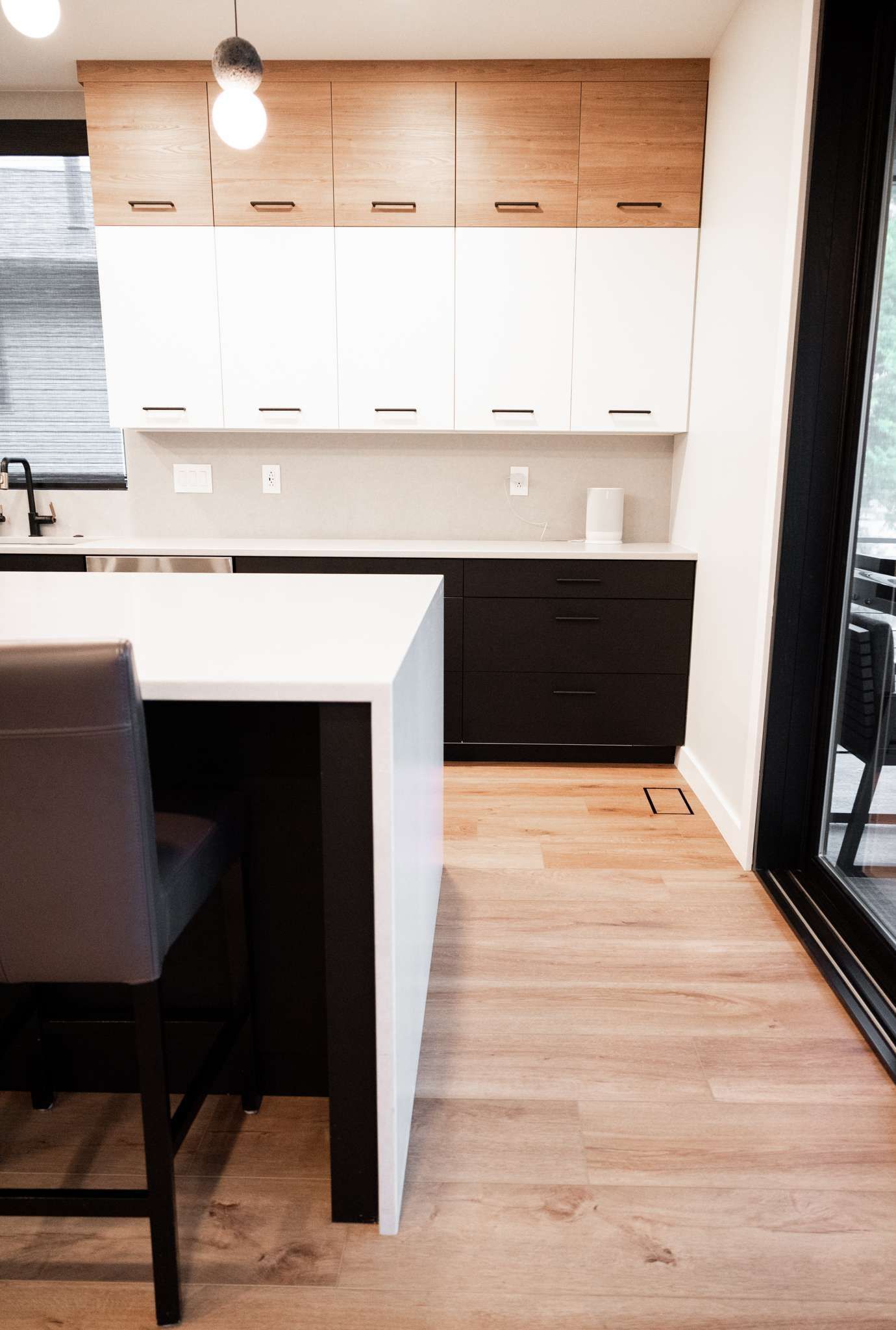 Modern kitchen with white cabinets, wood accents, island, and black-framed glass doors