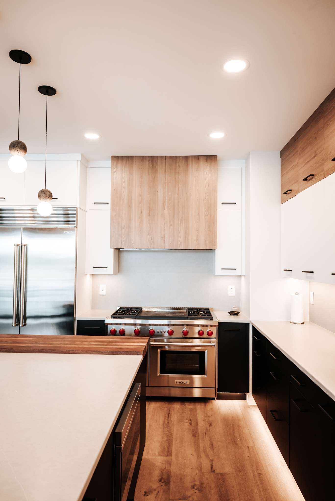Modern narrow kitchen with wood cabinets, stainless steel appliances, and a wood floor