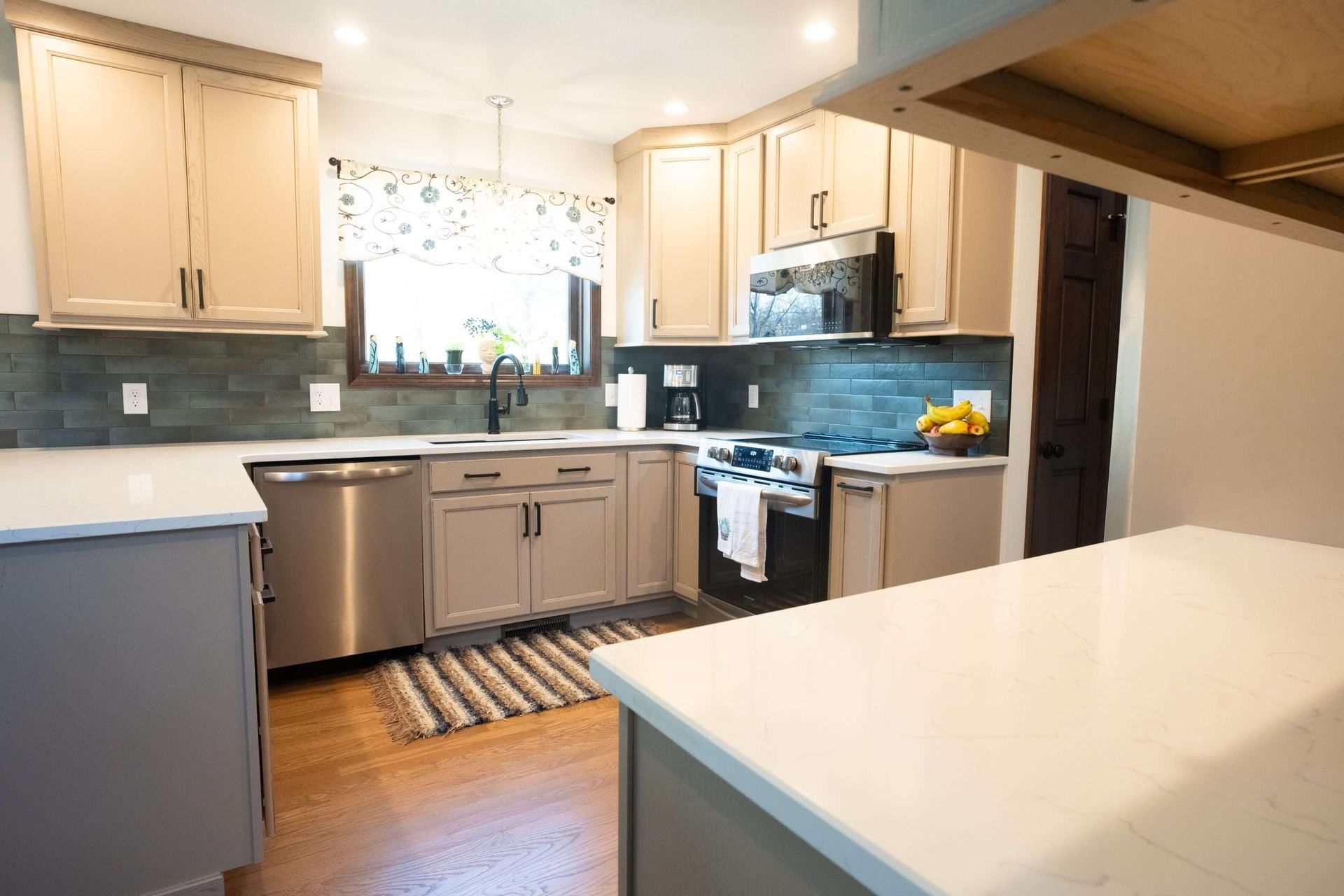 Bright modern kitchen with stainless appliances, light wood cabinets, and white countertops
