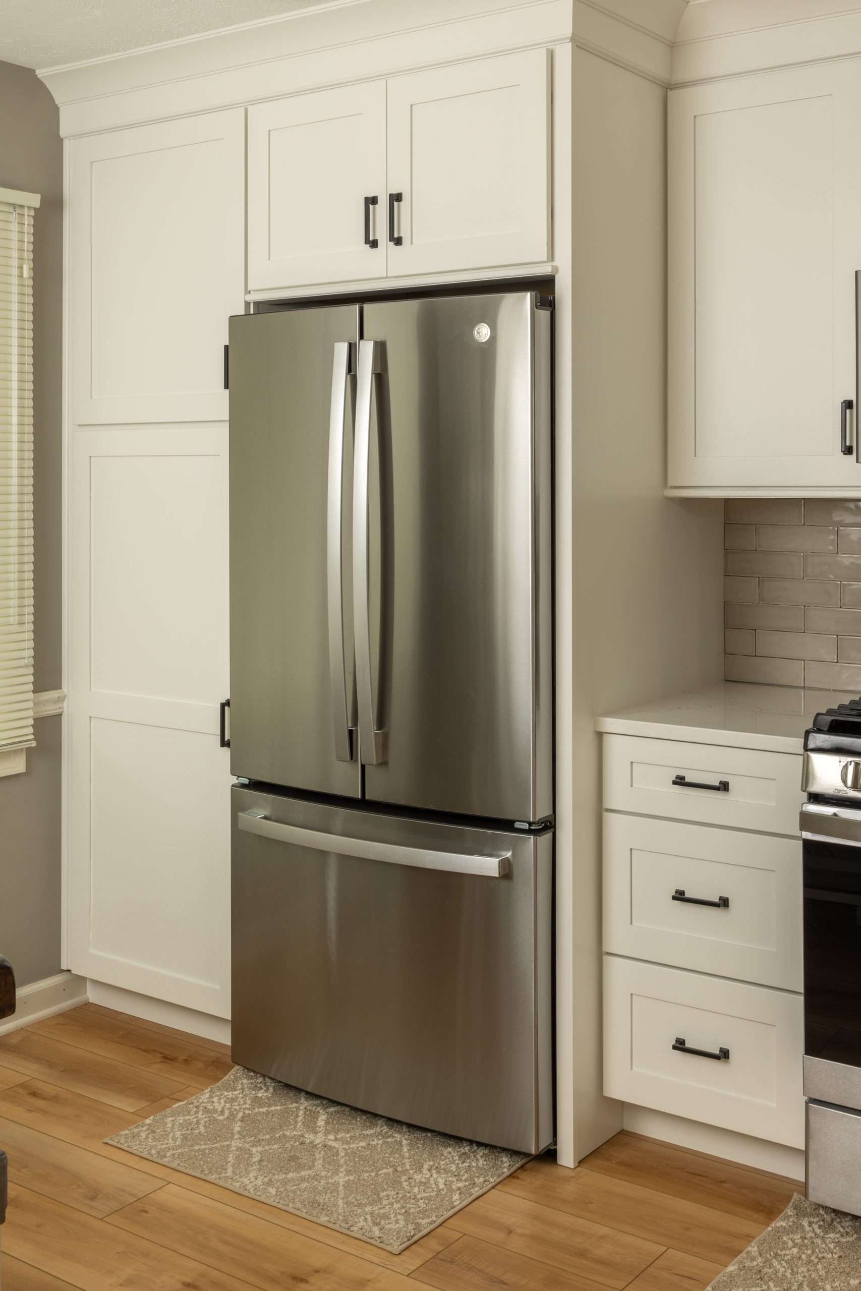 Modern kitchen with stainless steel refrigerator, white cabinets, and light tile backsplash