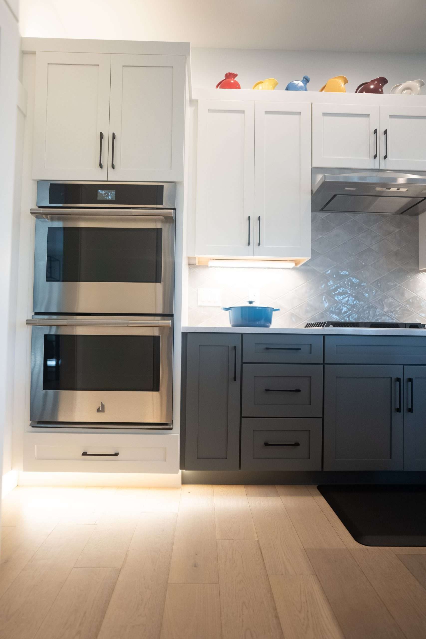 Modern kitchen with white cabinets, built-in stainless steel oven, and blue pot on the counter