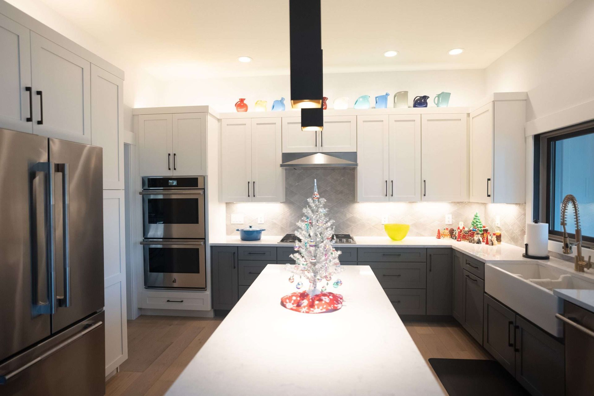 Bright modern kitchen with white cabinets, stainless appliances, and a large island with a small centerpiece.