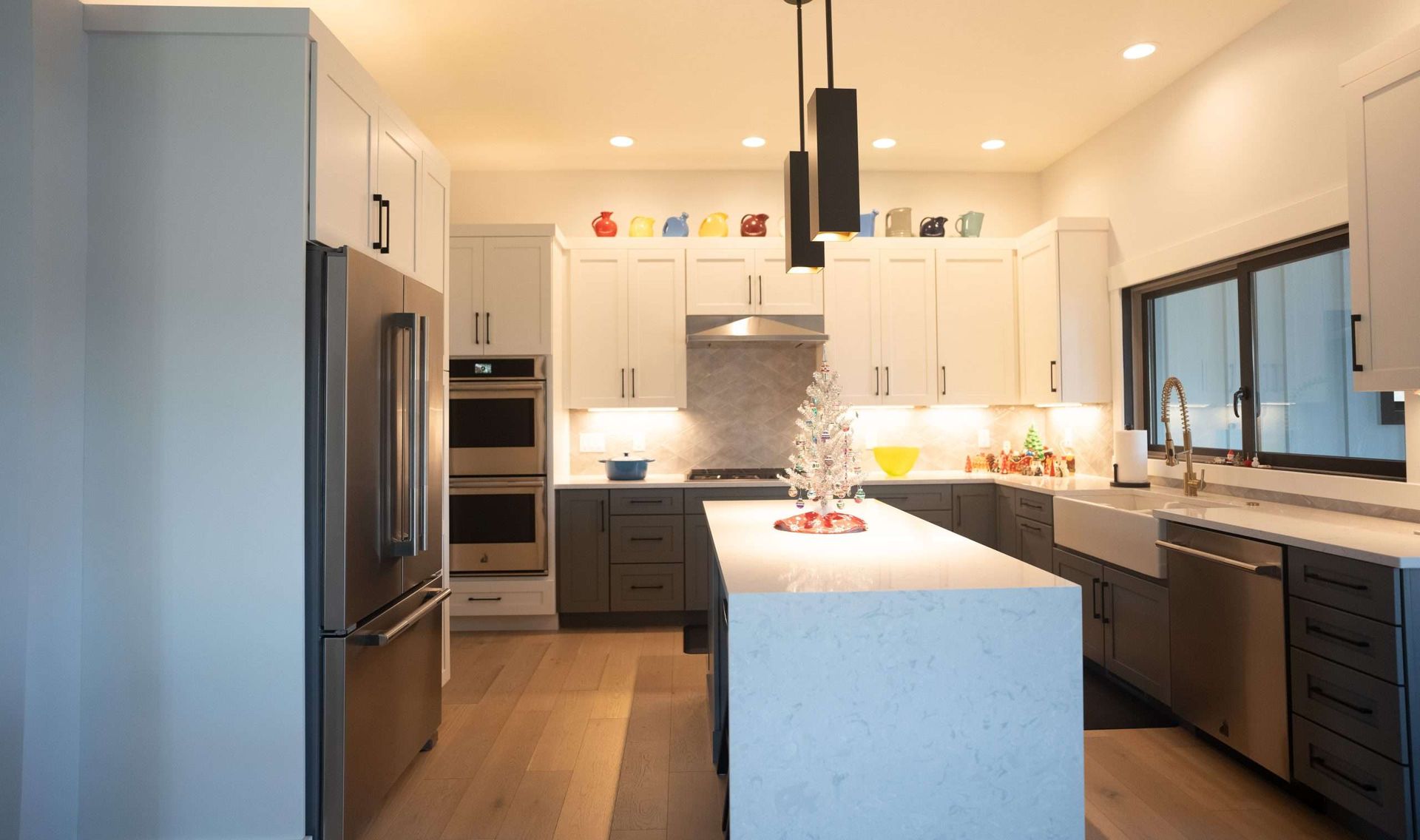 Bright modern kitchen with white cabinets, stainless steel appliances, and a central island with pendant lights.