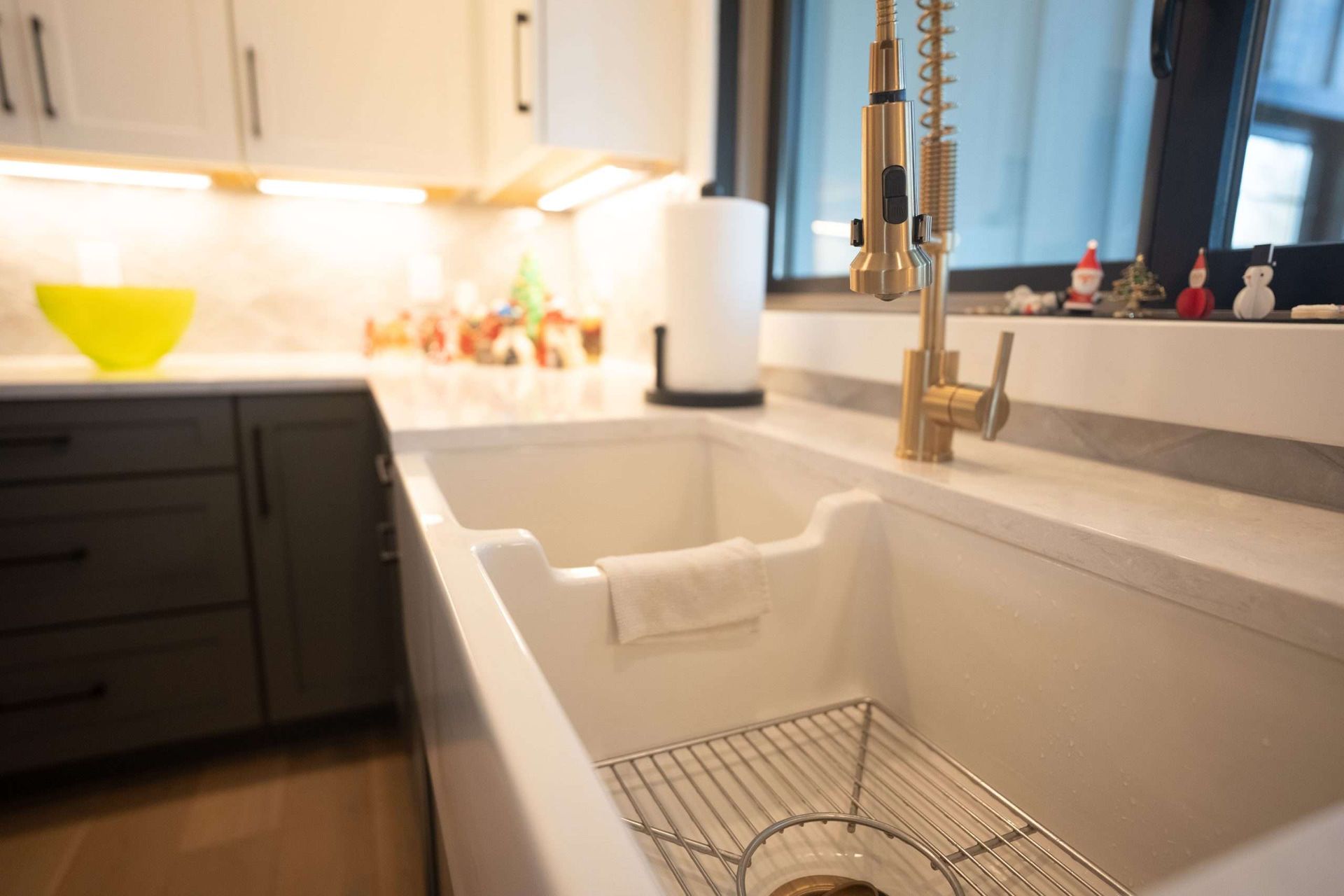 Modern kitchen with a white farmhouse sink, gold faucet, and black cabinets.