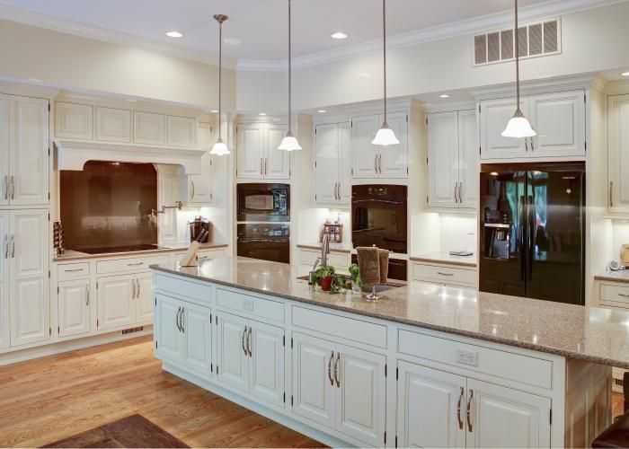 Bright white kitchen with a large island, granite countertops, and stainless steel appliances