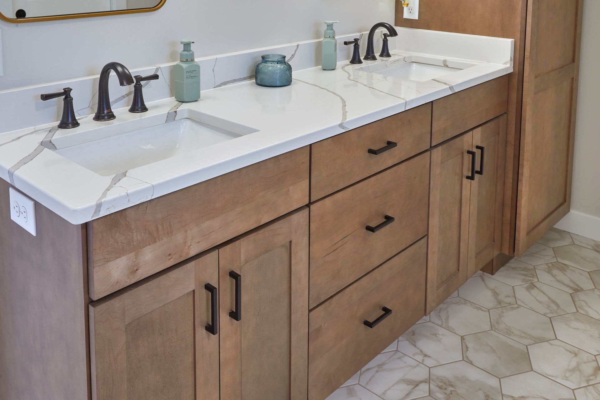 Double vanity bathroom sink with wood cabinets, black faucets, and hexagon tile floor
