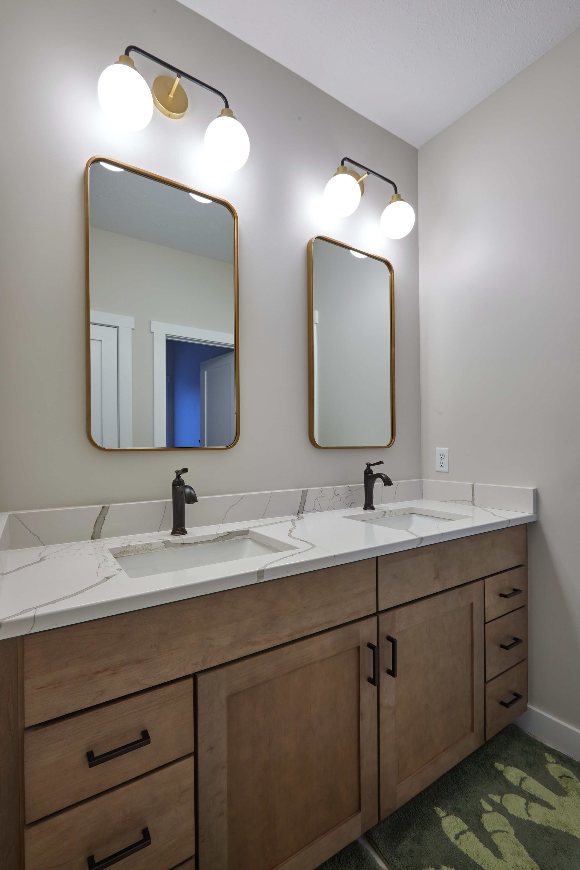 Modern bathroom vanity with dual sinks, wood cabinets, mirrors, and wall sconces