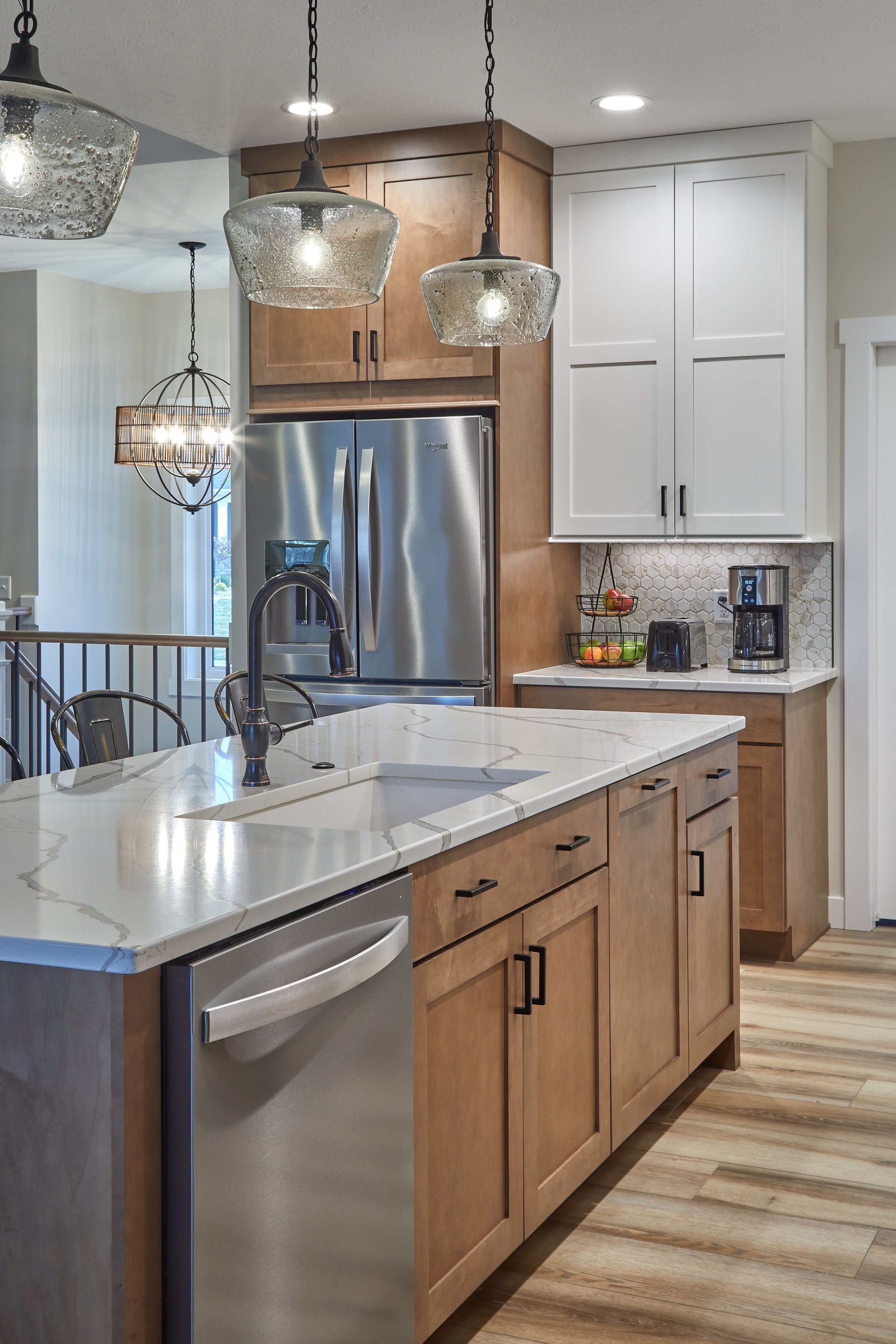 Modern kitchen with white and wood cabinets, stainless steel fridge, island, and pendant lights