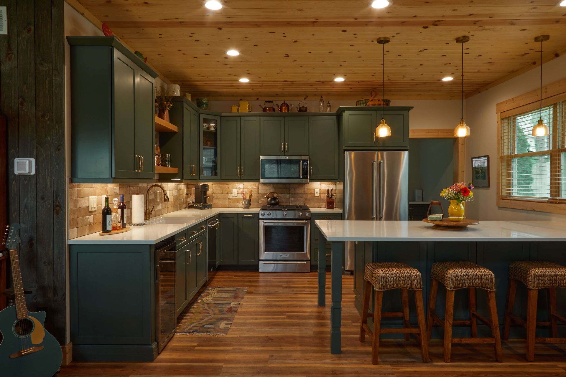 Warm wood kitchen with dark cabinets, stainless appliances, and a large island with stools and flowers.