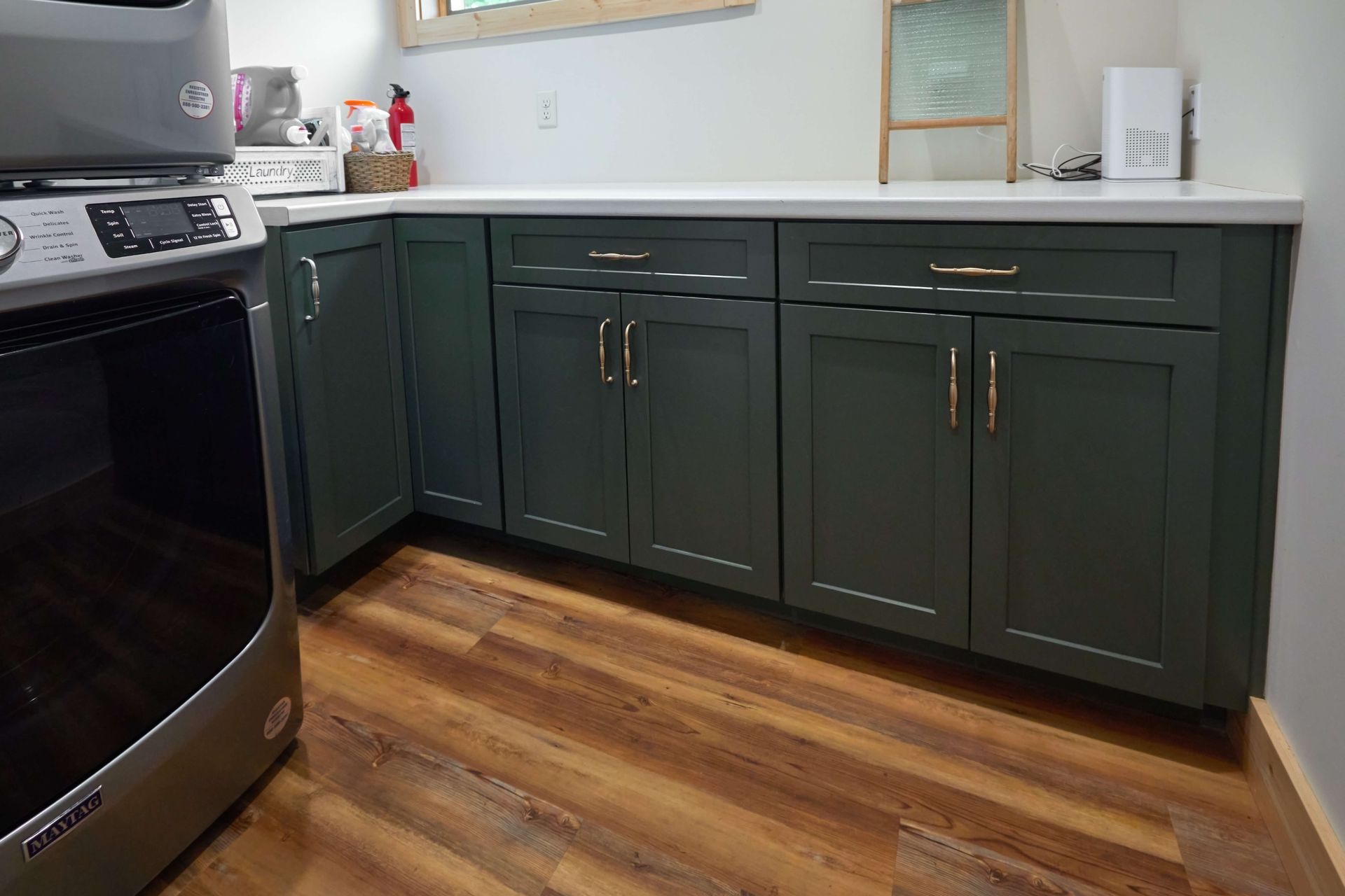 Kitchen with dark green cabinets, white countertop, and wood flooring next to a black stove