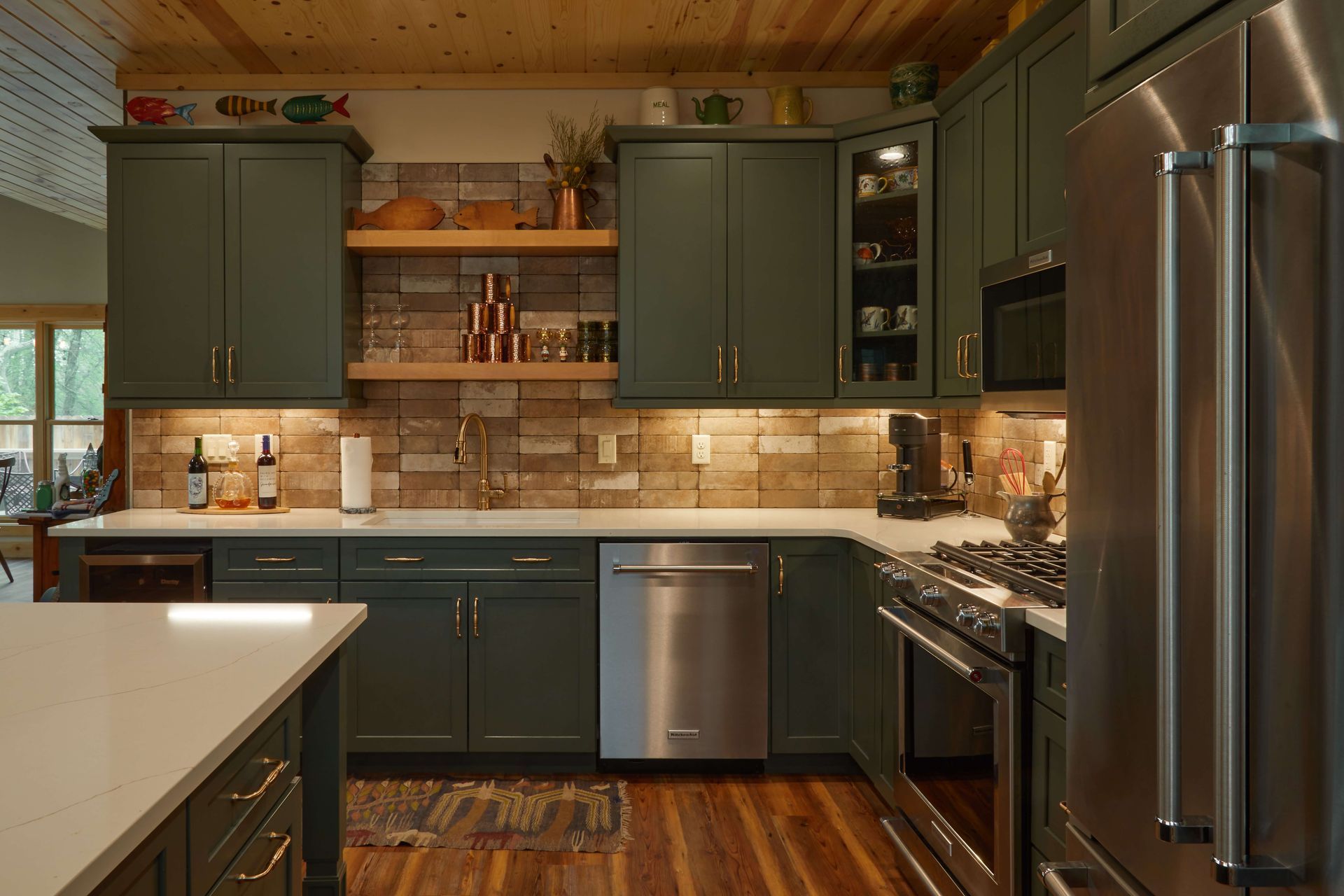 Modern kitchen with dark green cabinets, stainless steel appliances, wood ceiling, and tiled backsplash