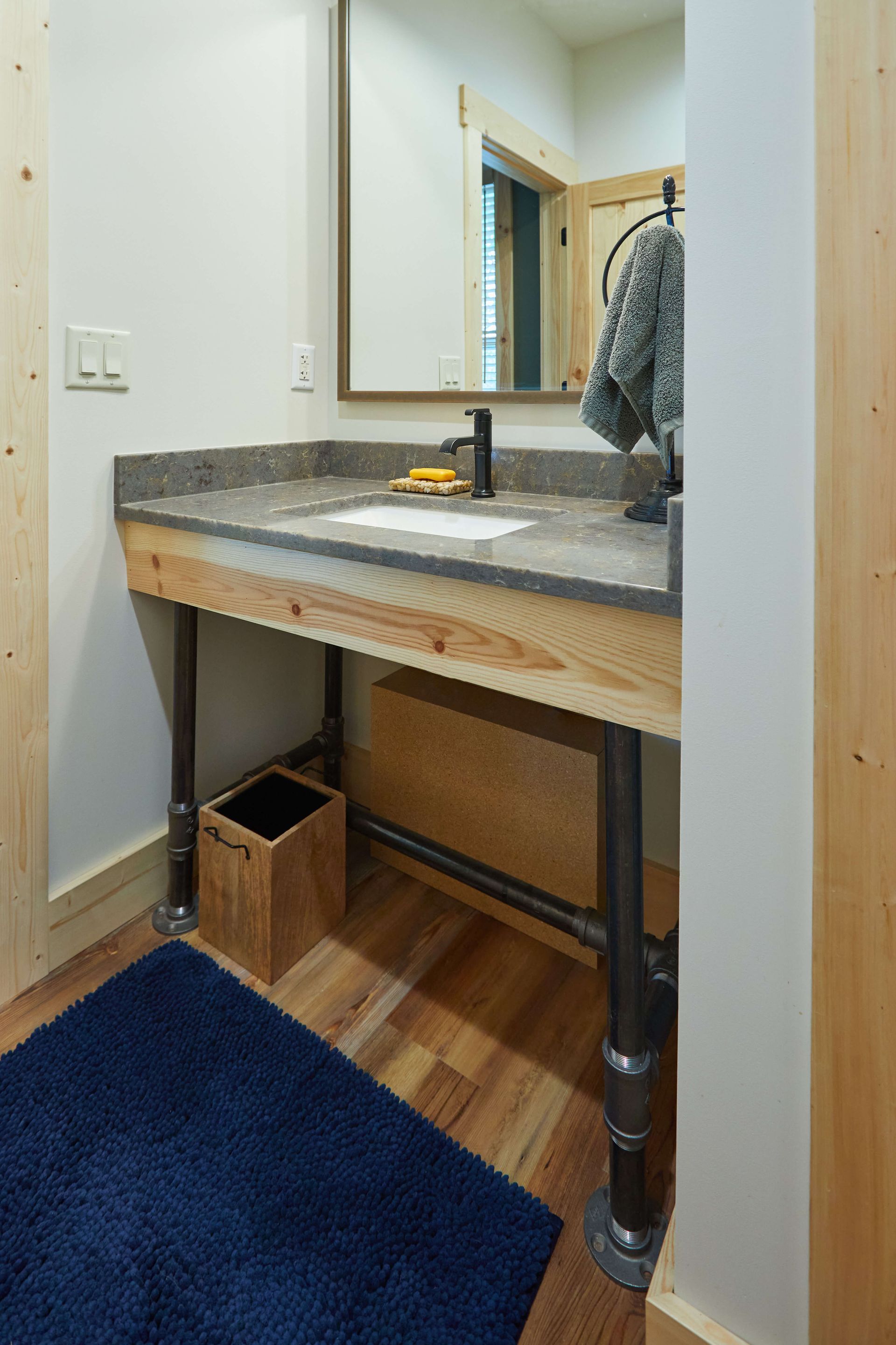 Bathroom vanity under construction with exposed plumbing, a mirror, and a person partially visible in the background