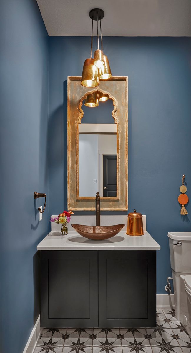 Blue powder room with ornate gold-framed mirror, vessel sink, and patterned tile floor