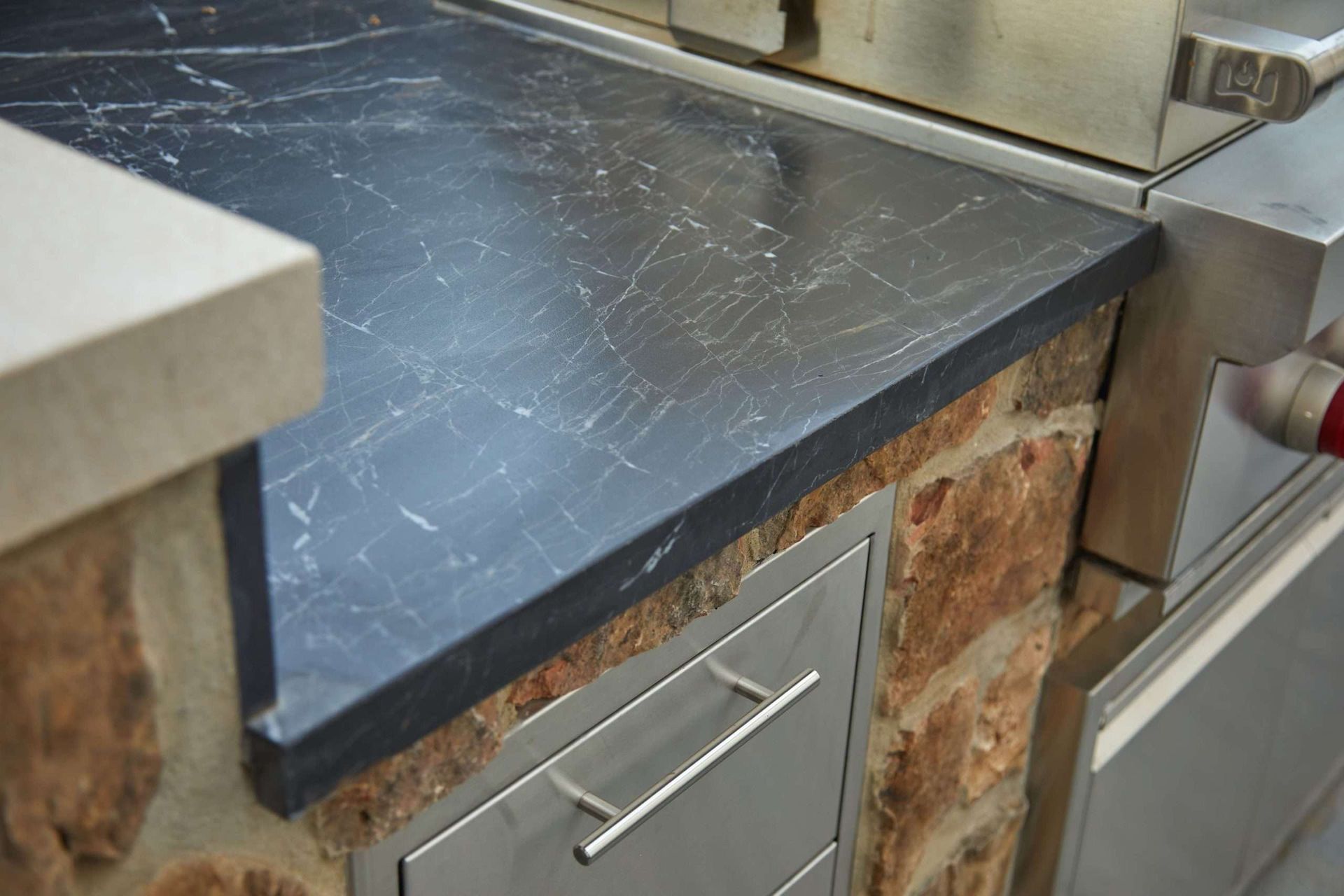 Black stone countertop on brick base with a drawer pull in a kitchen