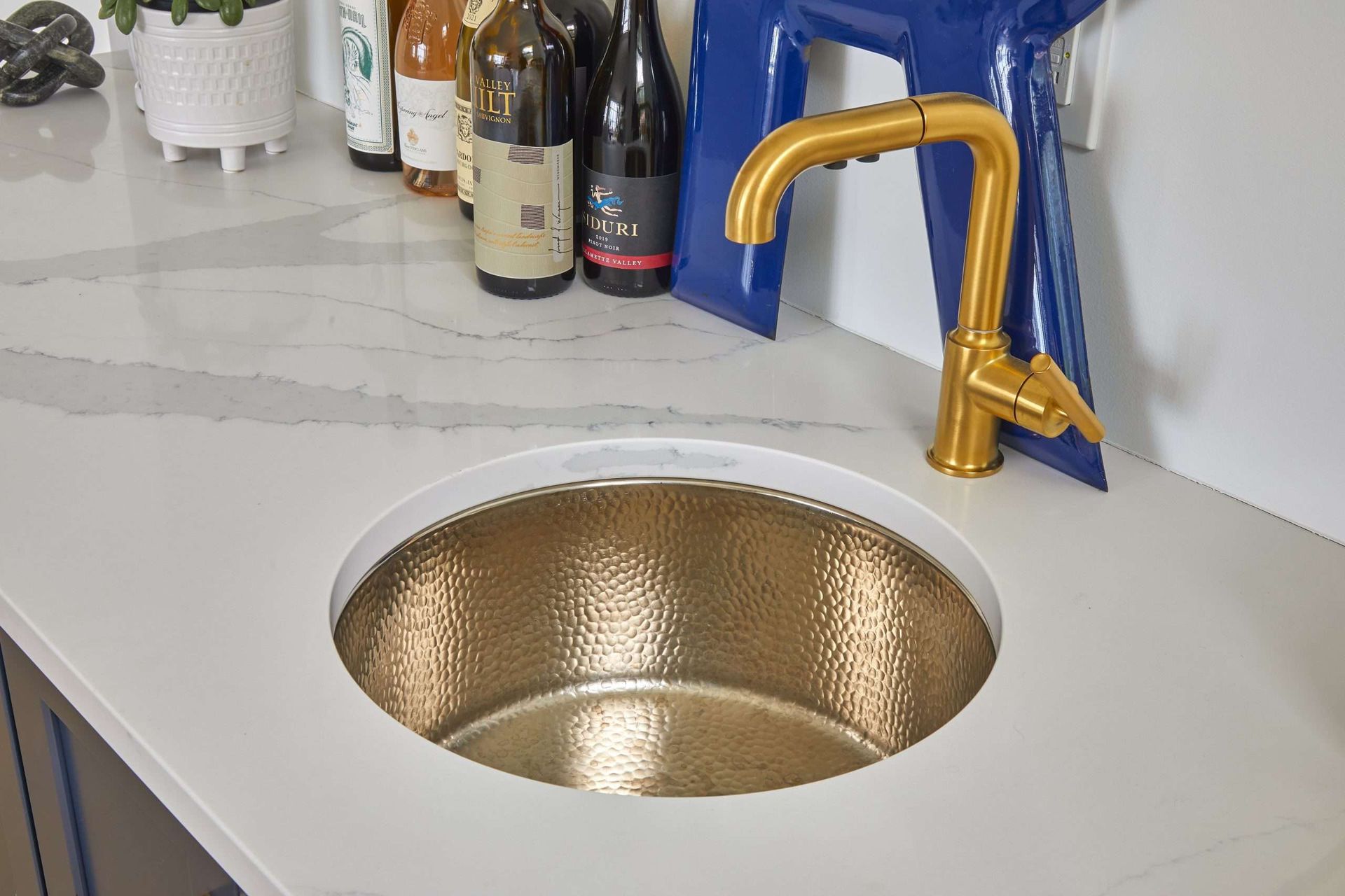 Gold sink with a curved brass faucet on a white countertop.