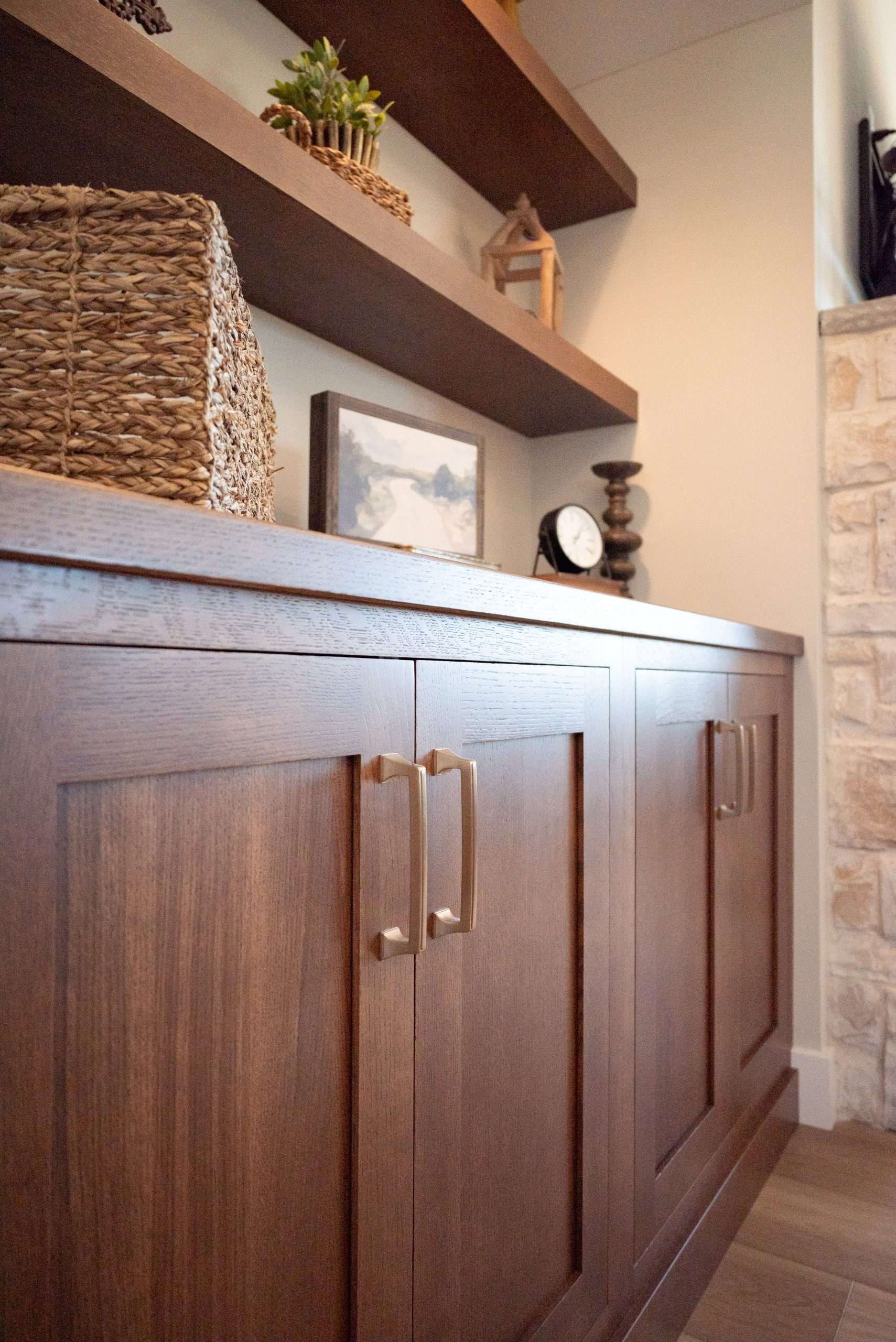 Wooden cabinet with brass handles below wall shelves in a modern home interior