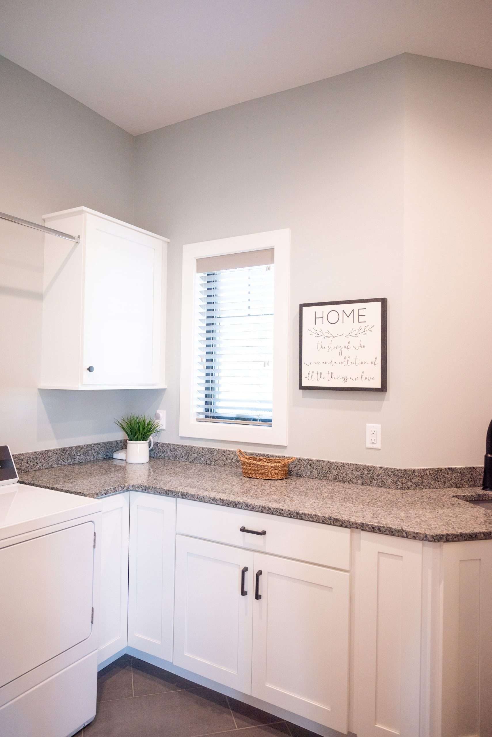 Bright white kitchen corner with granite countertops, white cabinets, and a small window above the counter.