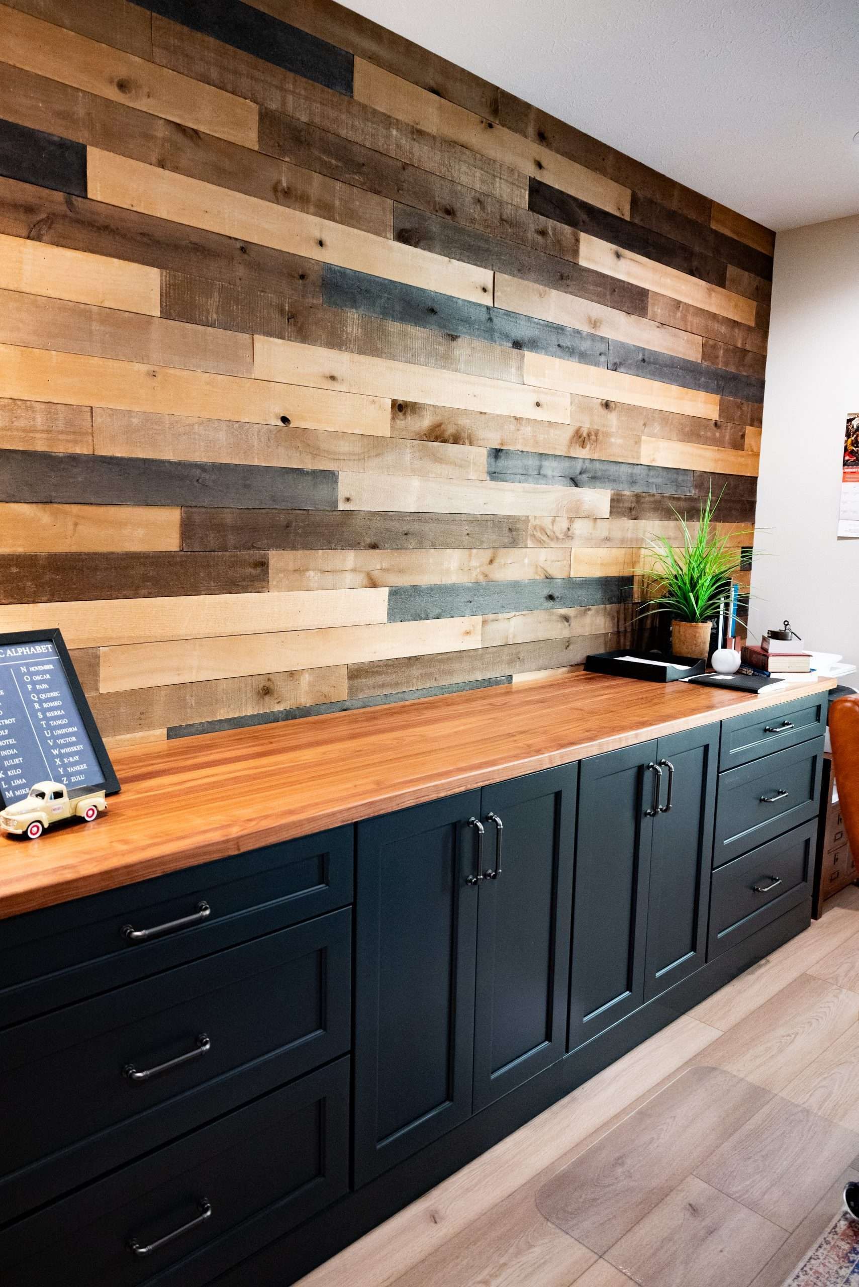 Modern kitchen with black cabinets, wooden countertop, and a multicolored wood accent wall.