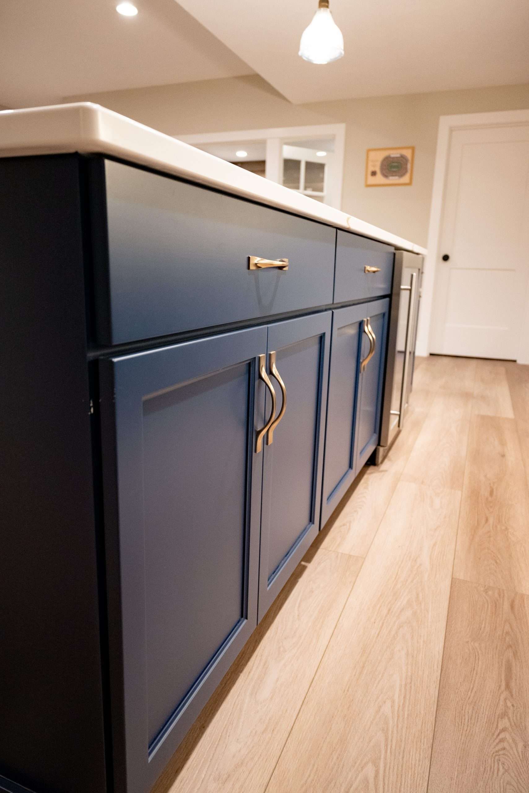 Blue kitchen island cabinets with brass handles in a bright modern kitchen