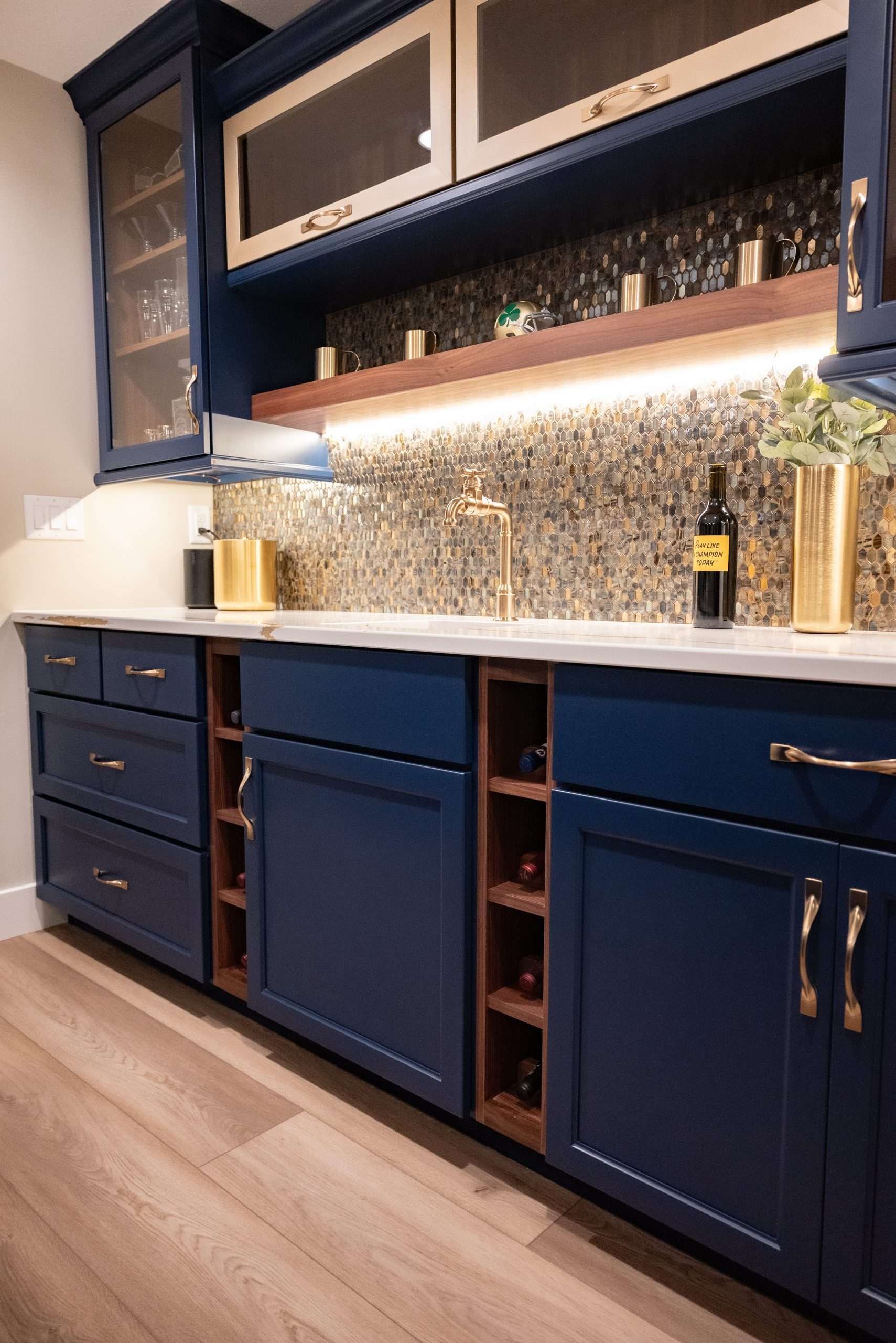 Blue kitchen cabinets with open shelving, mosaic backsplash, and warm under-cabinet lighting