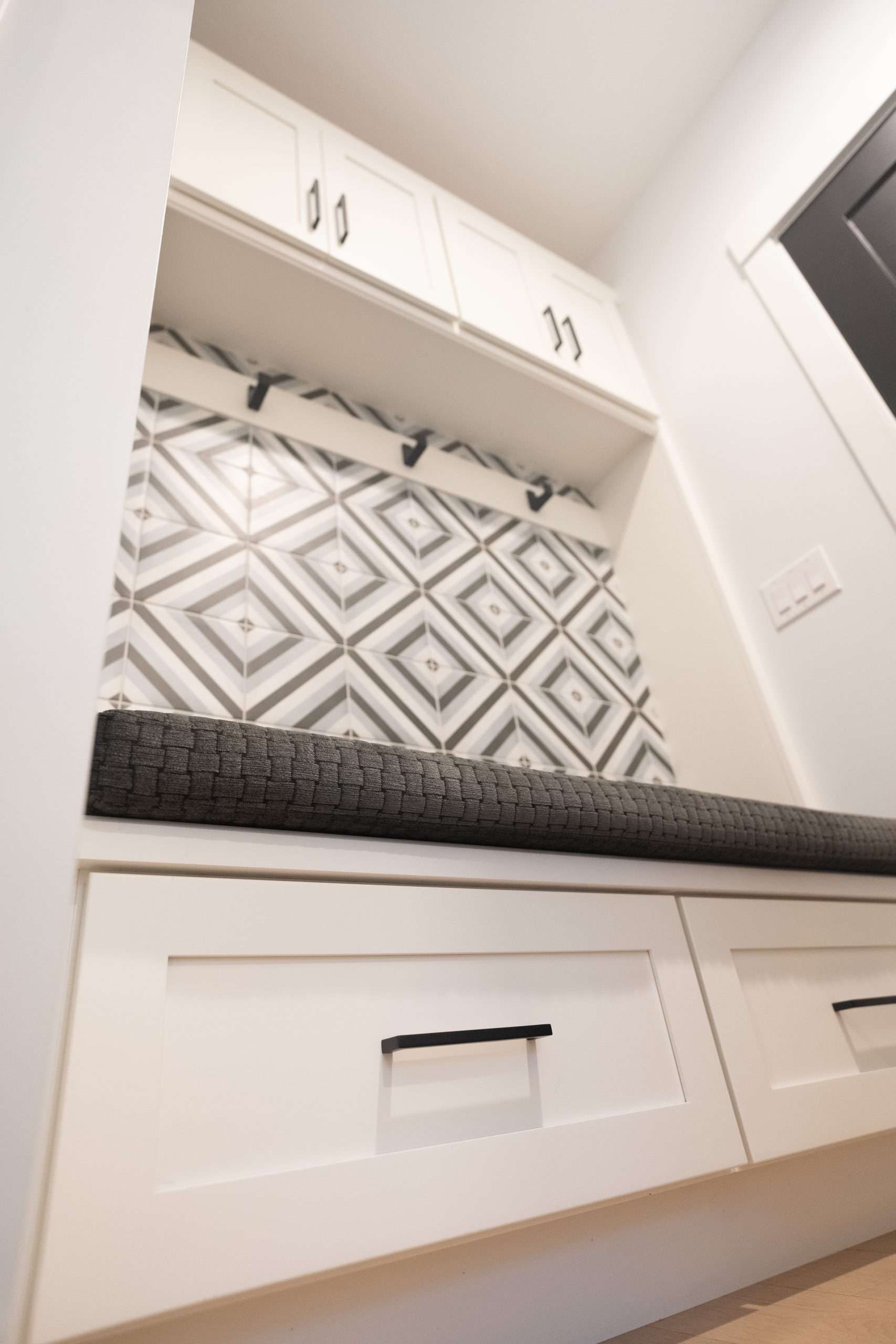 Built-in kitchen cabinetry with white cabinets, patterned backsplash, and dark countertop