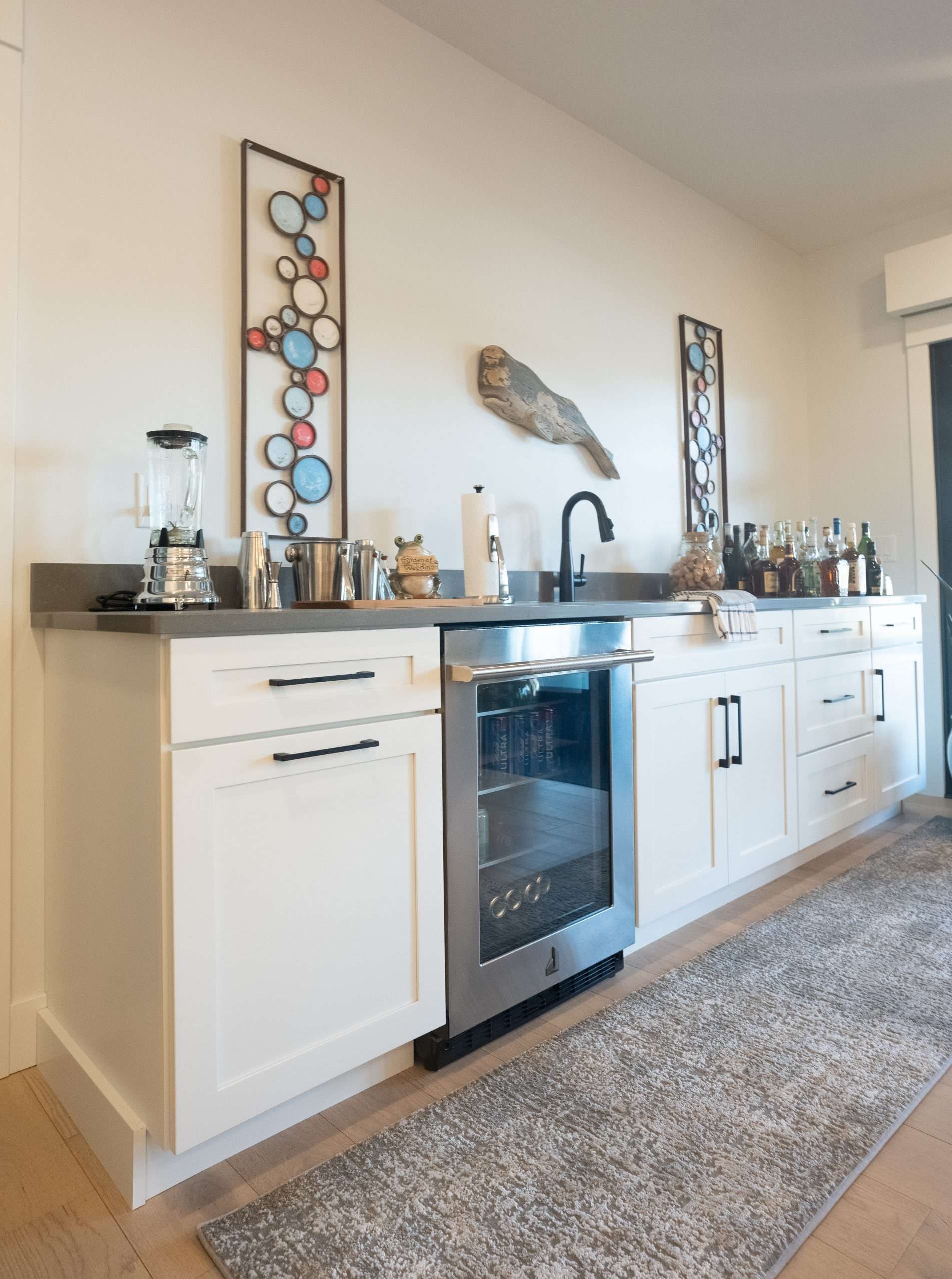 Modern kitchen with white cabinets, black oven, dark countertops, and decorative wall art