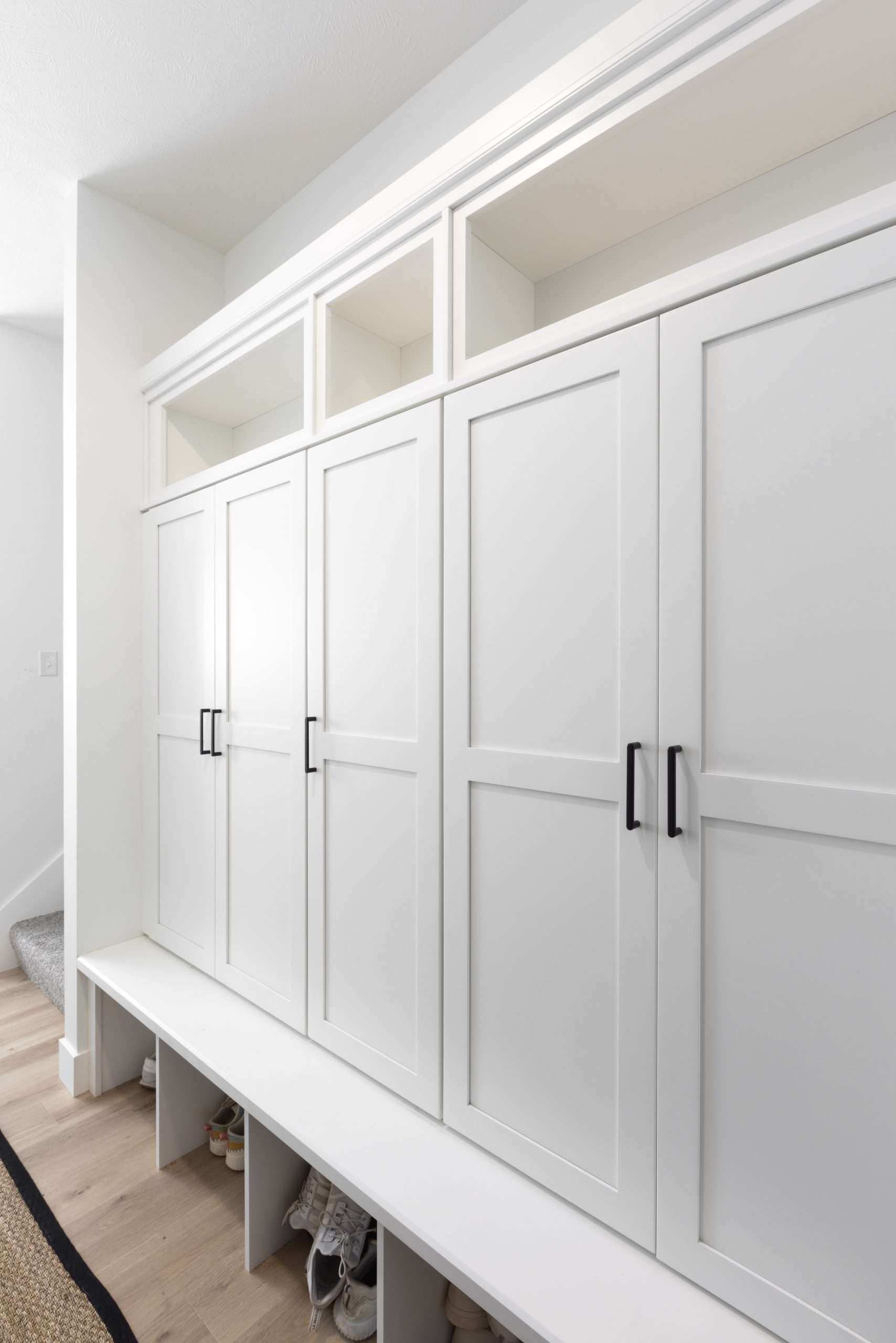 White built-in hallway cabinets with paneled doors and open cubbies above and below.