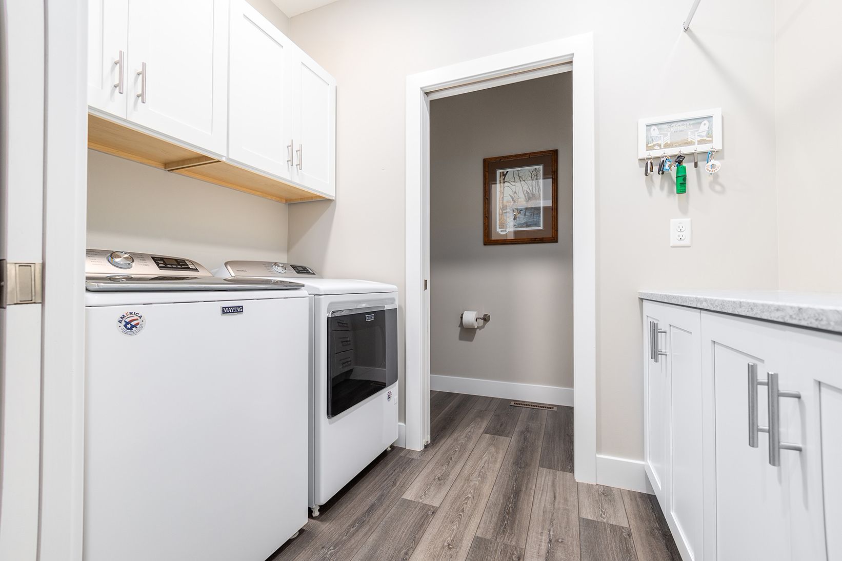 Laundry room with white cabinets, washer, dryer, and a doorway into a bathroom