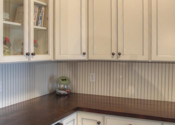 Kitchen corner with cream cabinets, striped backsplash, and dark wood countertop