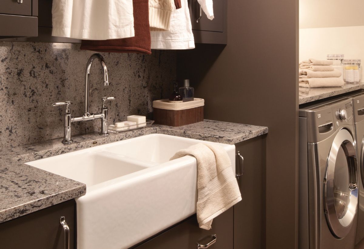 Laundry room with farmhouse sink, granite counter, hanging clothes, and washer-dryer units