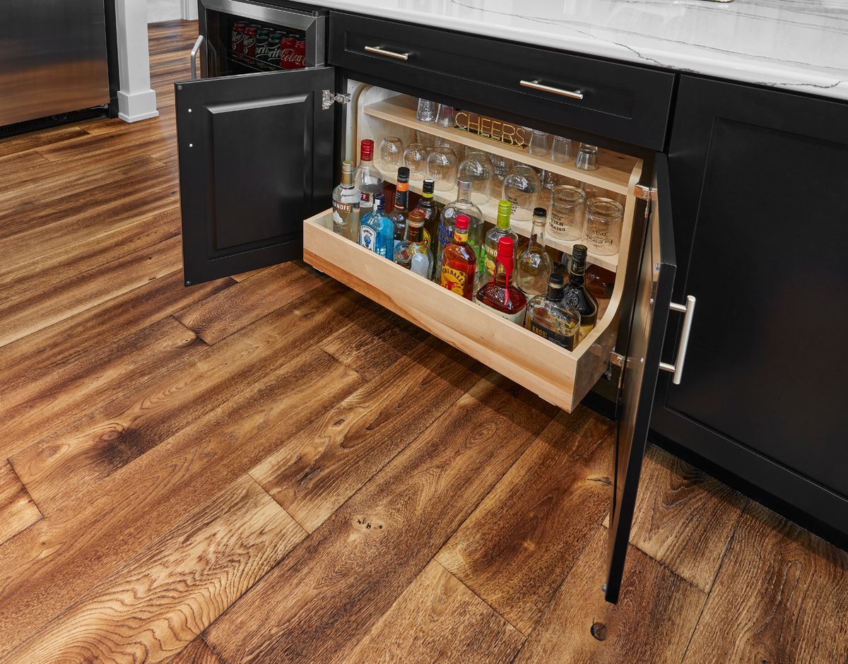 Open under-counter liquor display with bottles on a lighted tray in a modern kitchen