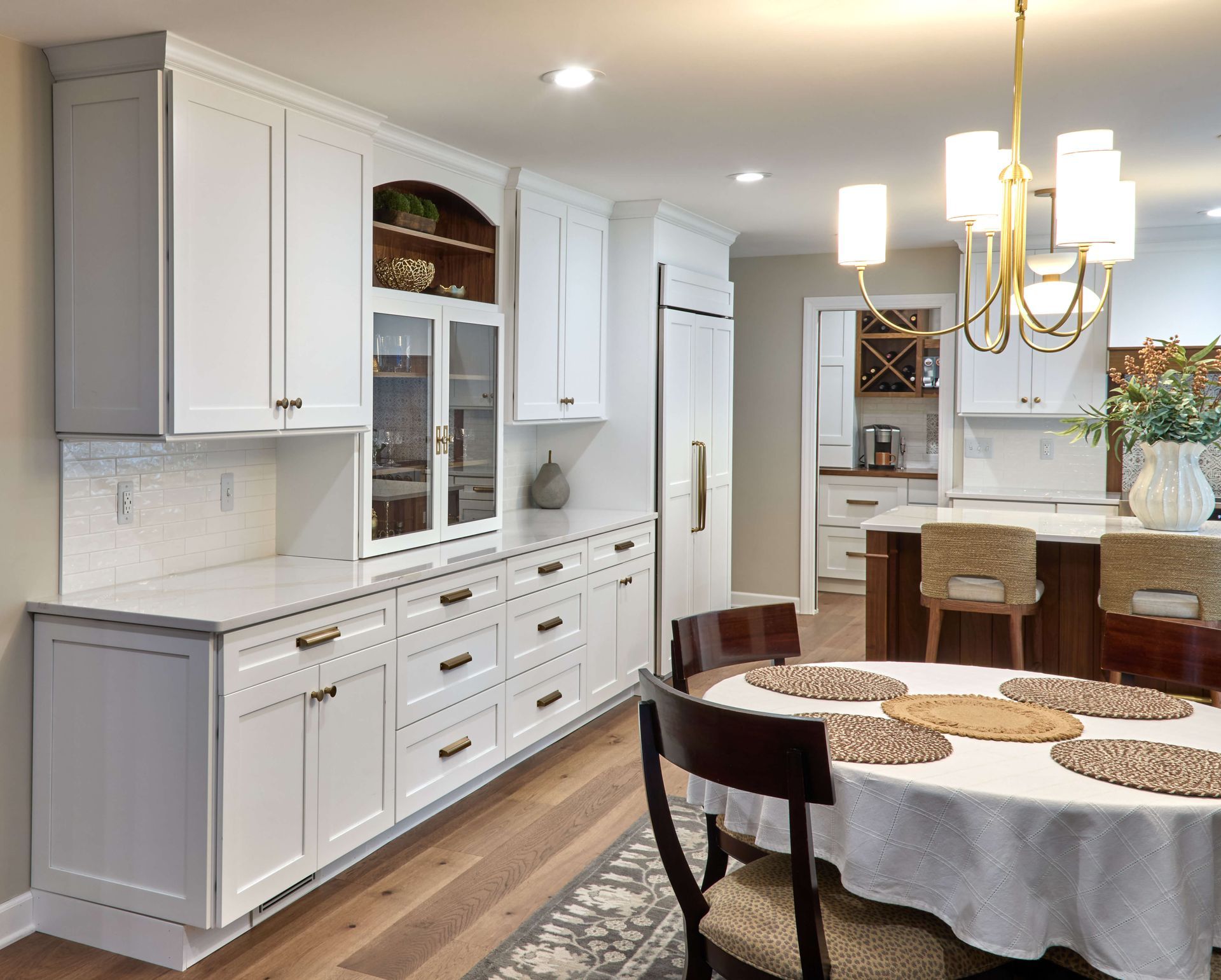 White kitchen cabinets with a dining area; chandelier, round table, and chairs.