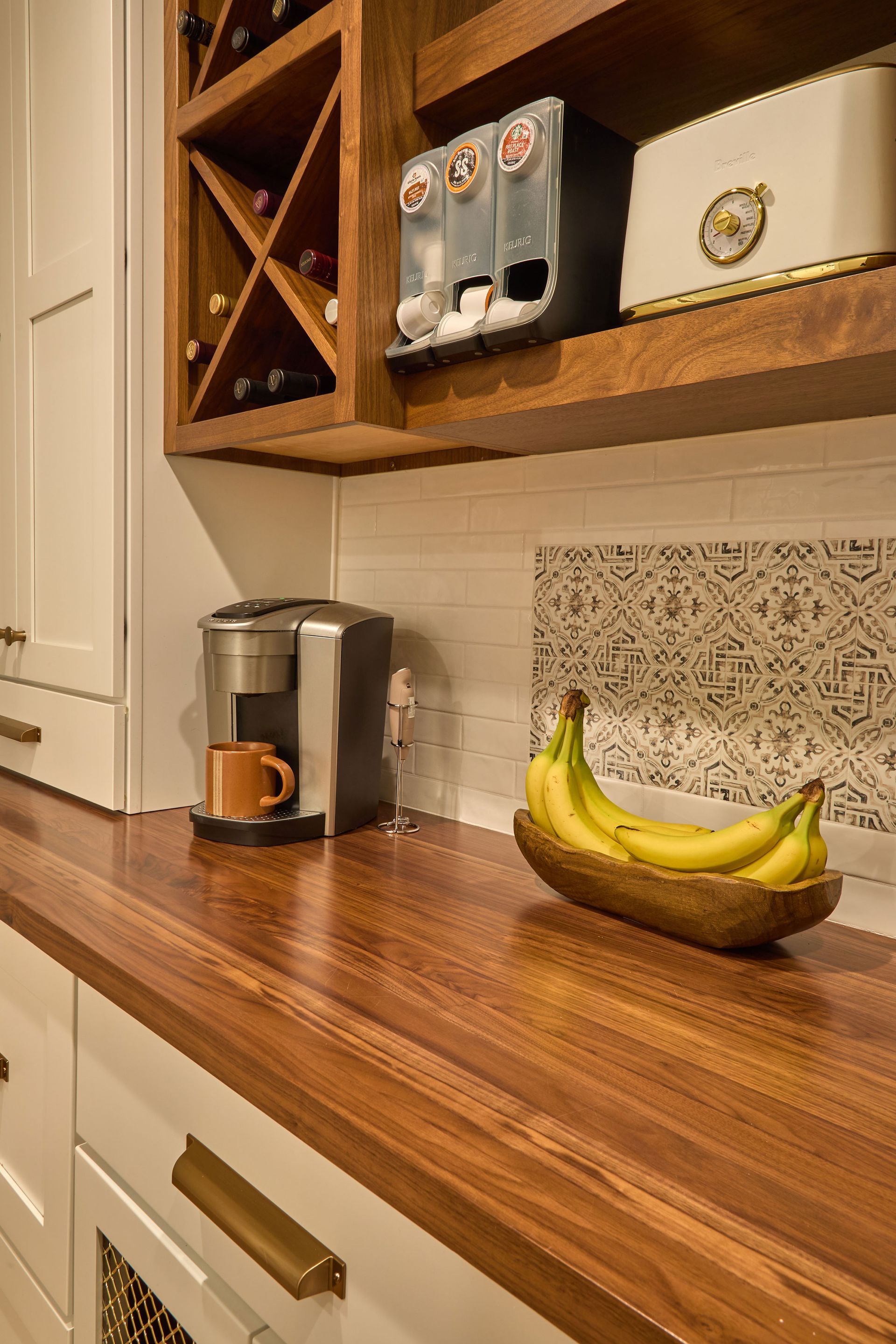 Wooden kitchen counter with coffee maker, bananas in a bowl, and shelves above.